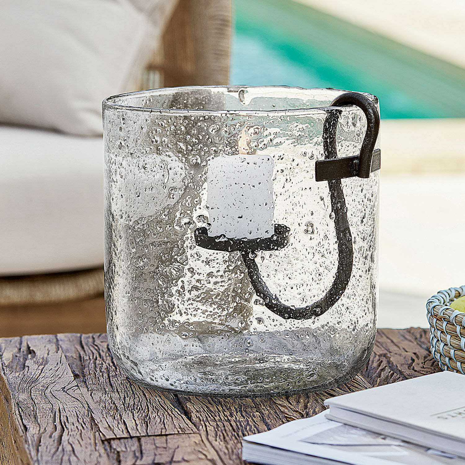 Glaswindlicht mit Luftblasen und schwarzem Metallgriff auf rustikalem Holztisch