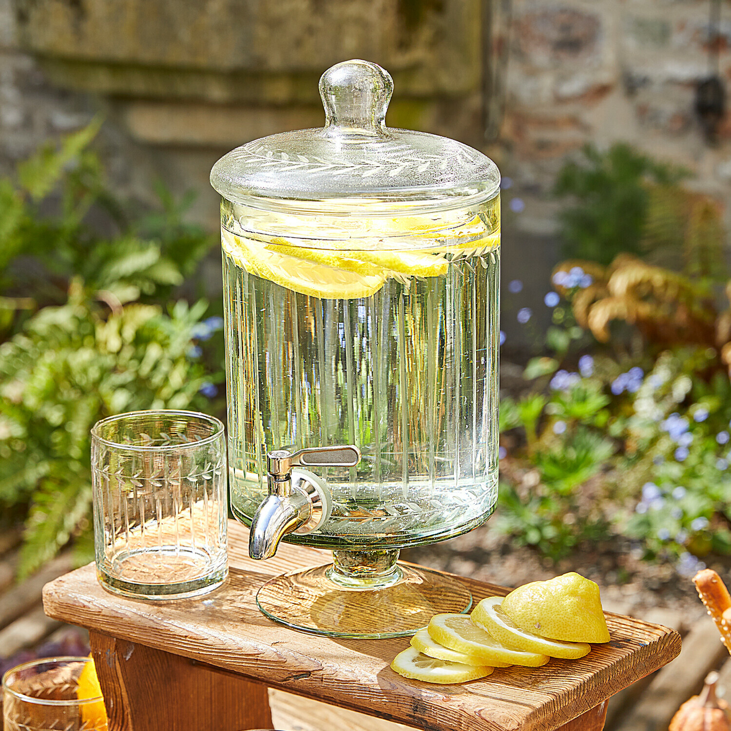 Getränkespender Makiya Glas-Getränkespender mit Deckel und Zapfhahn, Zitronenscheiben, auf Holztisch im Garten