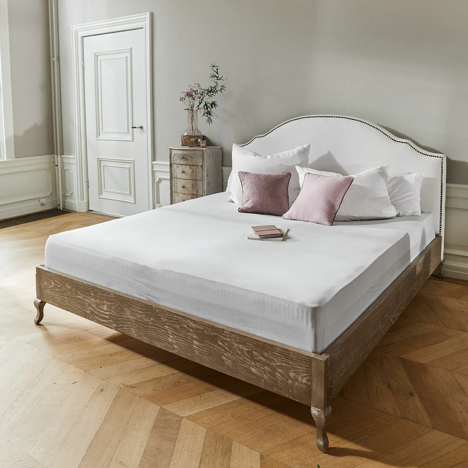 Bett mit Holzrahmen und weiß gepolstertem Kopfteil mit Ziernägeln im eleganten Vintage-Stil