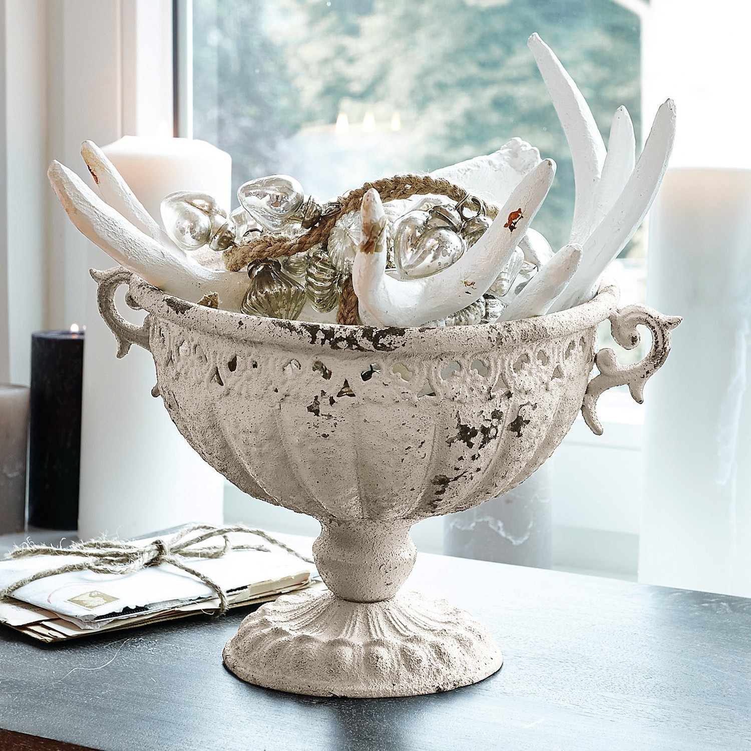 Dekorative weiße Metall-Schale im Vintage-Stil mit Verzierungen und Kerzen auf Tisch