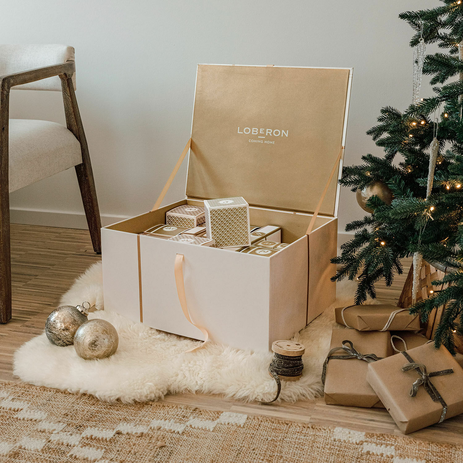 Große beige Aufbewahrungsbox mit Weihnachtsdekorationen neben Tannenbaum und Stuhl