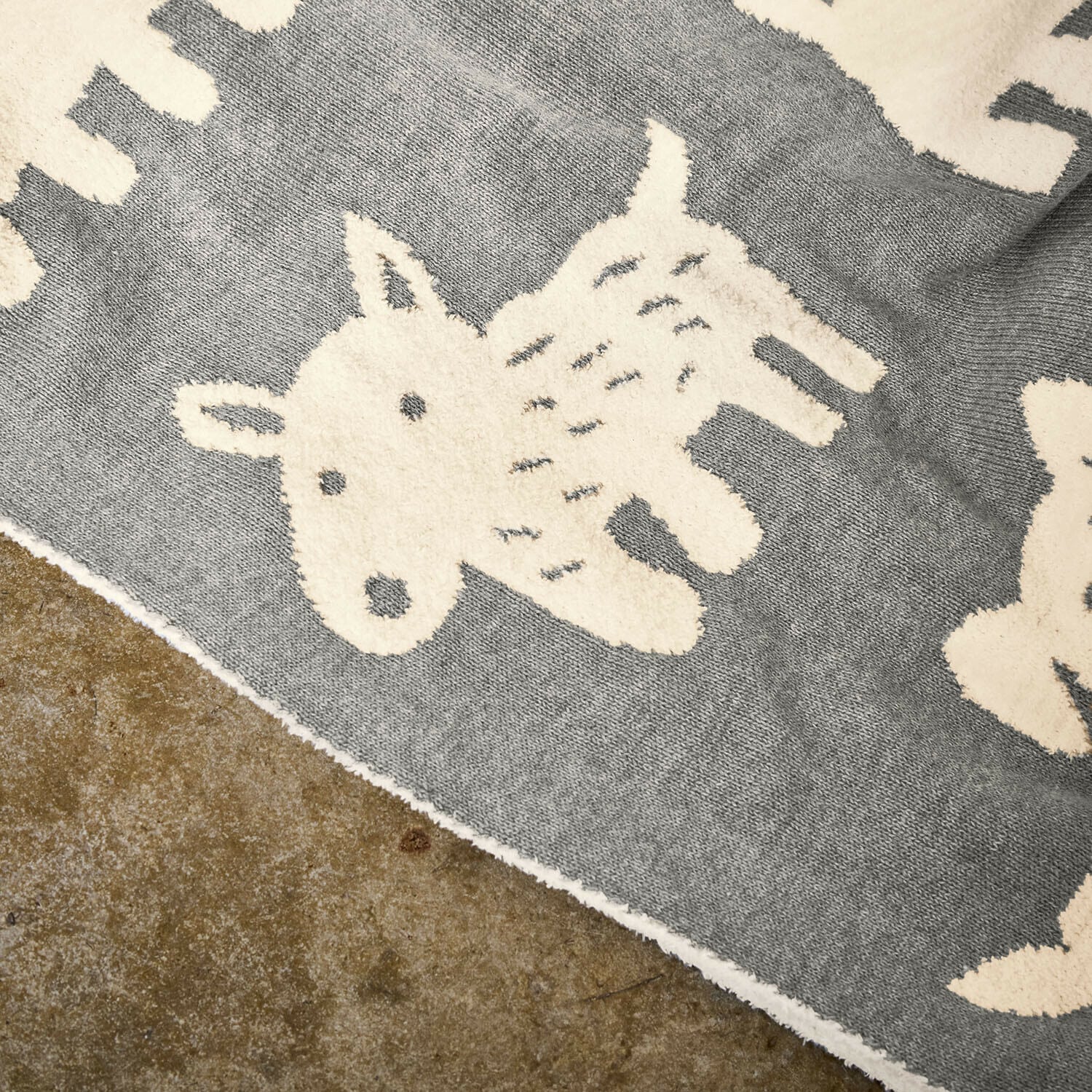 Grauer Teppich mit weichem cremefarbenem Tiermotiv, ideal für Kinderzimmer