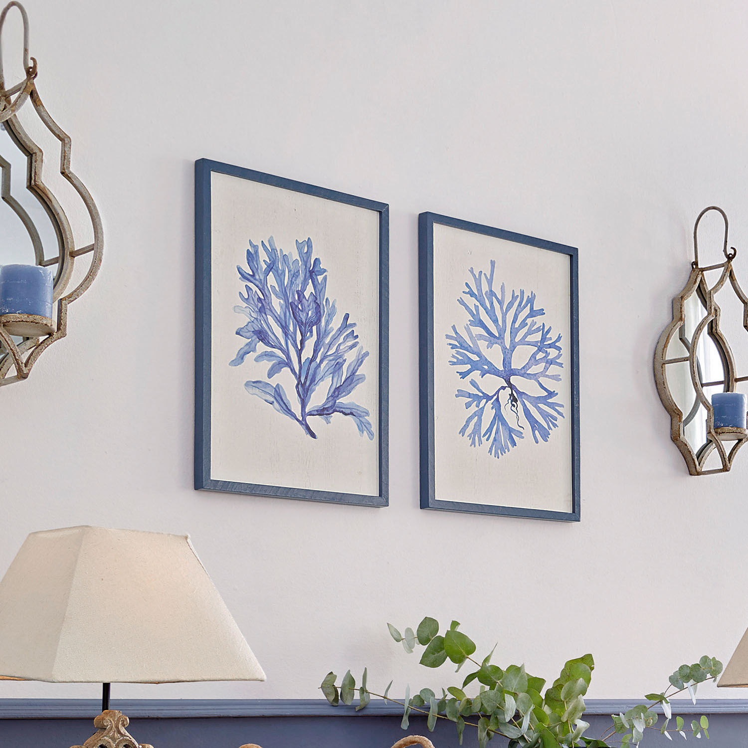 Zwei Bilder mit blauen Korallenmotiven in Holzrahmen an weißer Wand im Wohnzimmer