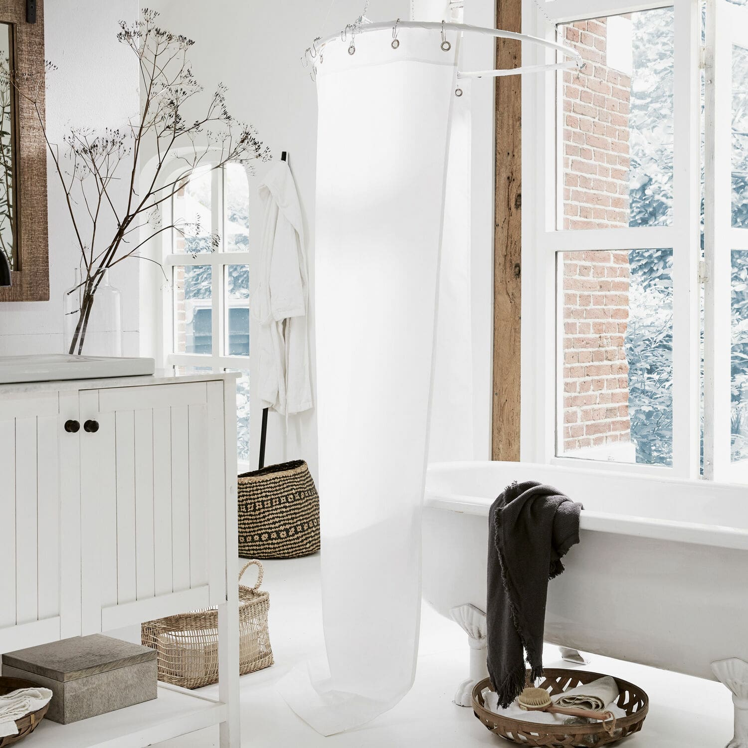 Helles Badezimmer mit weißer Badewanne auf Löwenfüßen und weißem Duschvorhang im skandinavischen Stil