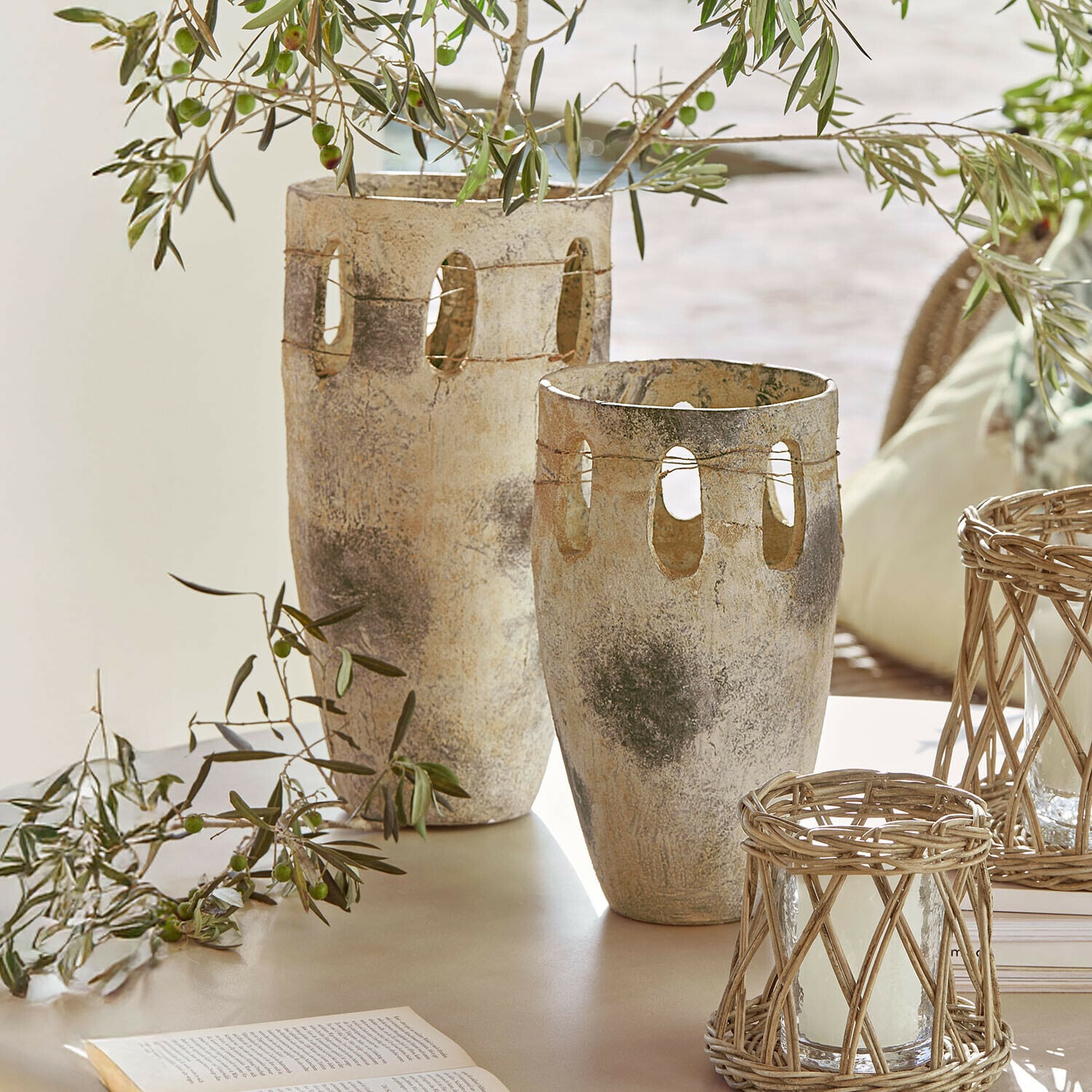 Vase 2er Set Delunas Zwei dekorative Vasen aus Stein in Beige-Grau mit Öffnungen und Olivenzweigen auf einem Tisch