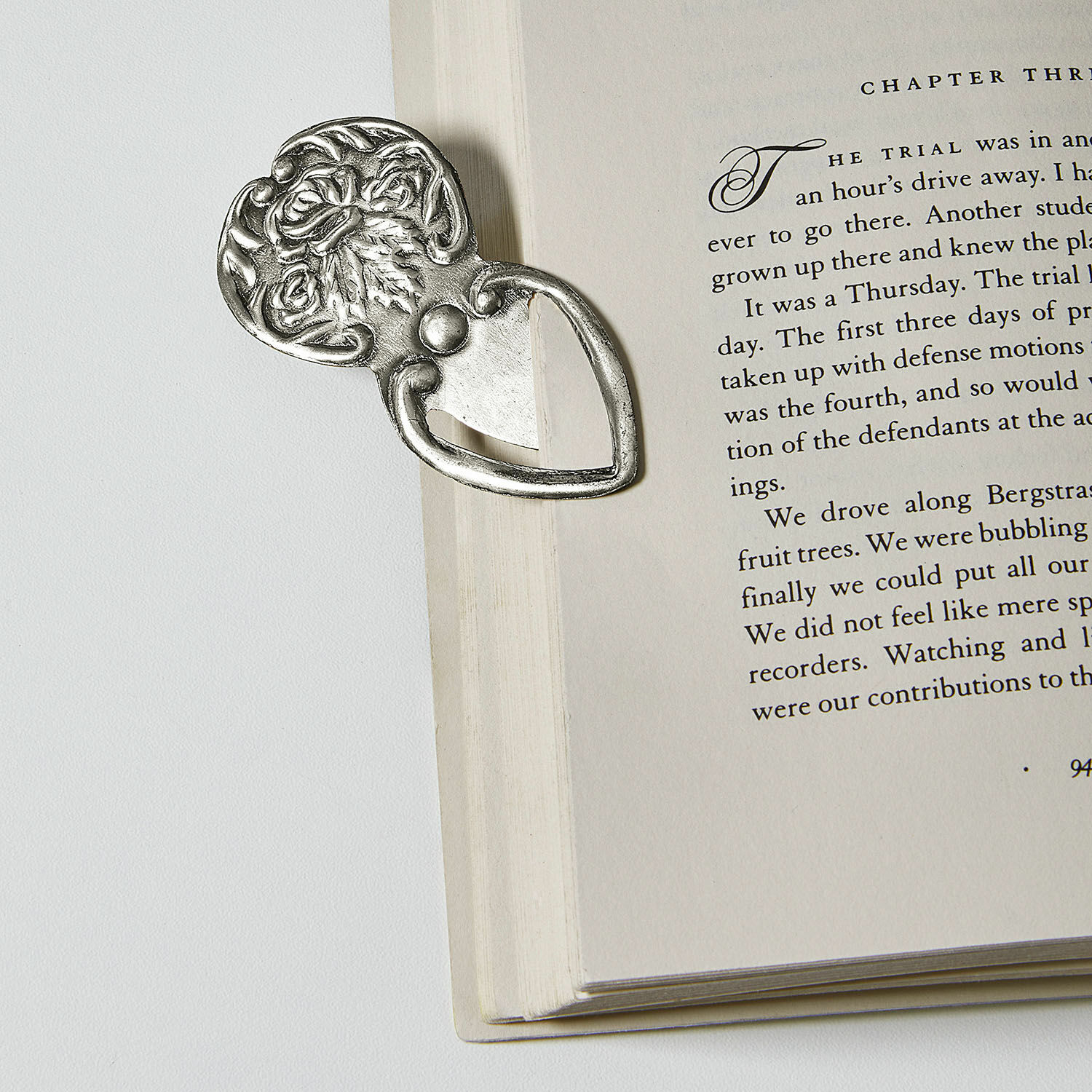 Metall-Lesezeichen mit verziertem Rosenmuster in Silber auf weißer Buchseite