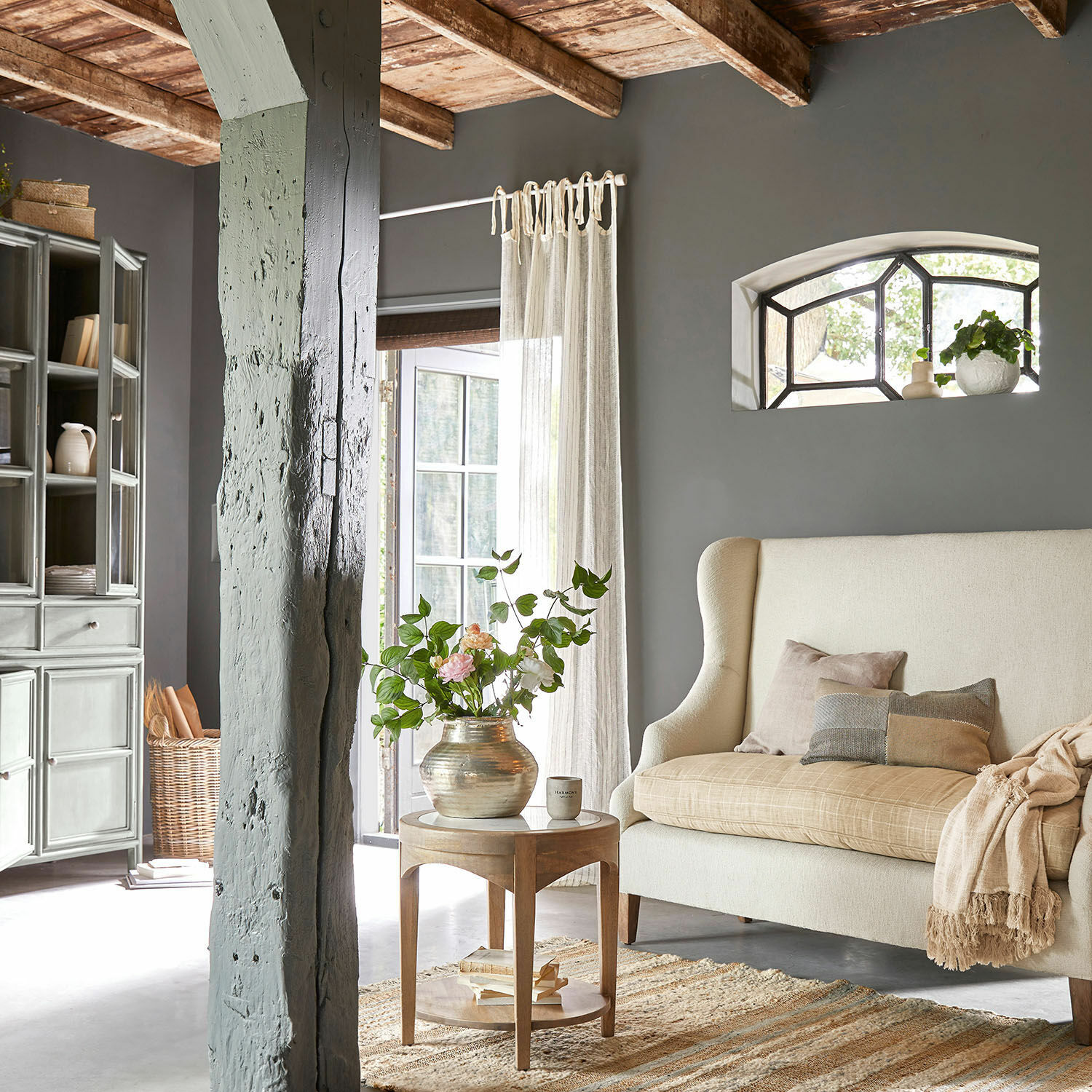 Gemütliches Wohnzimmer mit beigem Sofa, Holztisch und dekorativer Blumenvase im rustikalen Stil