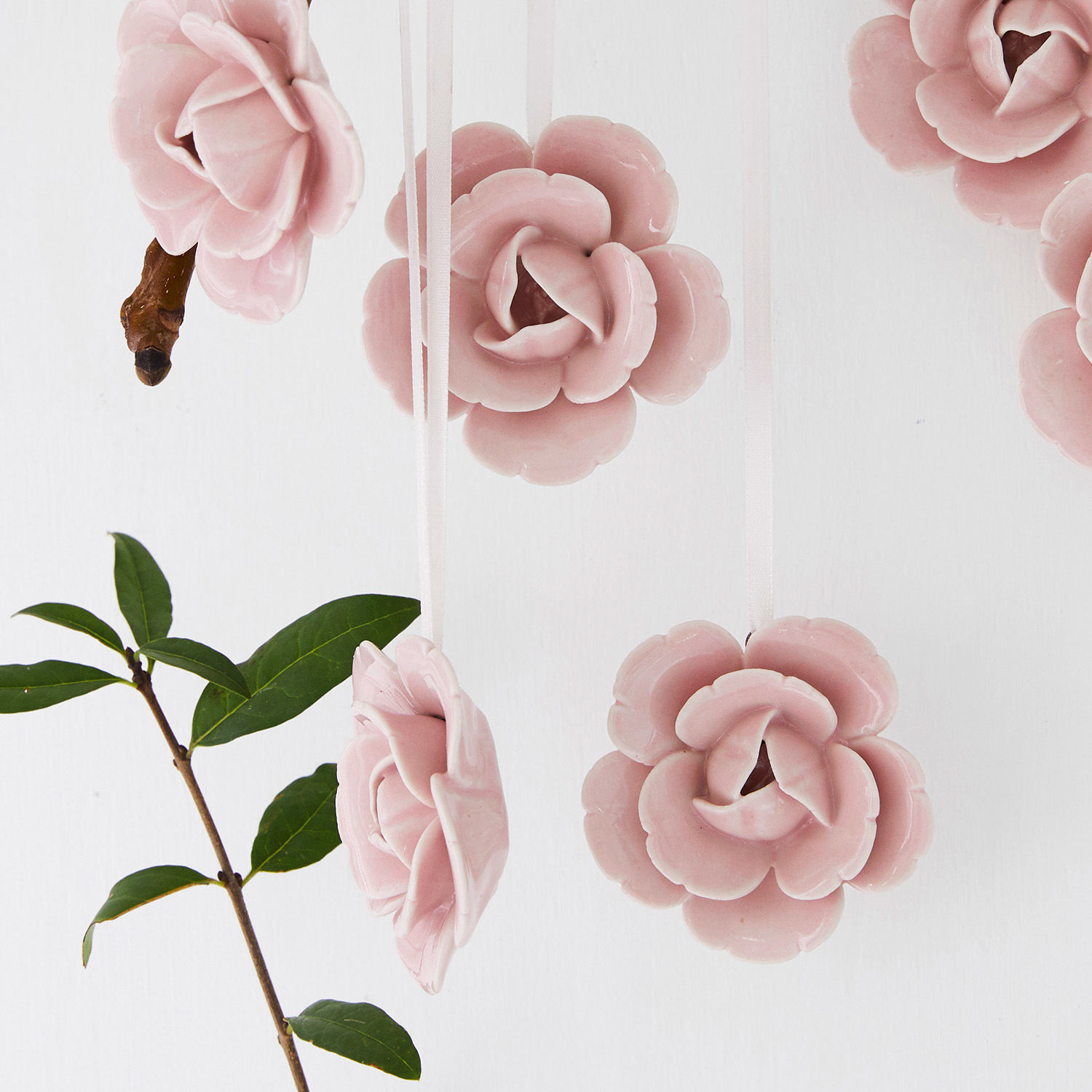 Rosa Keramikblumen an Bändern hängend, zarte Dekoration für Innenräume