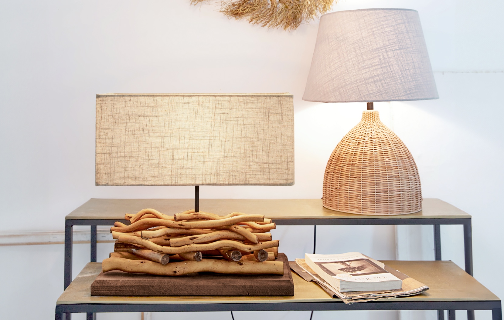 Zwei Tischlampen aus Naturholz und Korbgeflecht mit beigen Lampenschirmen auf Metalltisch