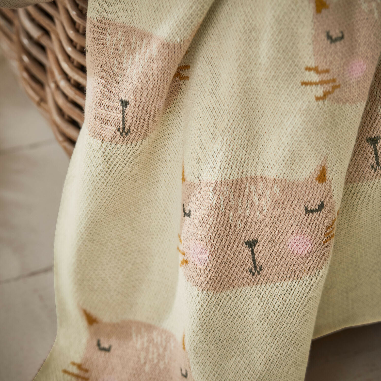 Weiche Baumwolldecke in Creme mit niedlichem rosa Katzenmuster, ideal für gemütliche Wohnräume
