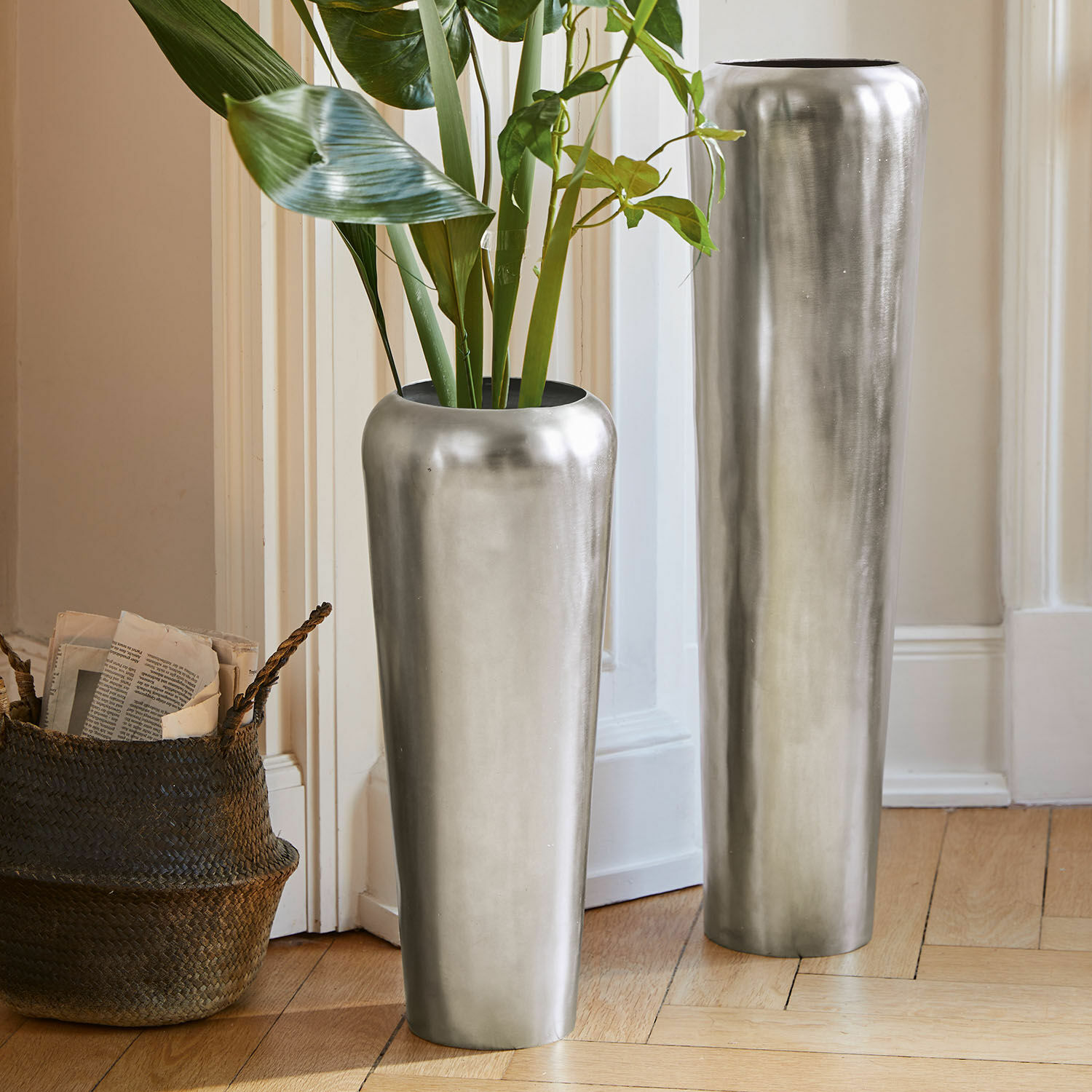 Bodenvase 2er Set Carolan Zwei hohe silberne Metallvasen auf dem Boden in hellem Raum mit grünen Pflanzen
