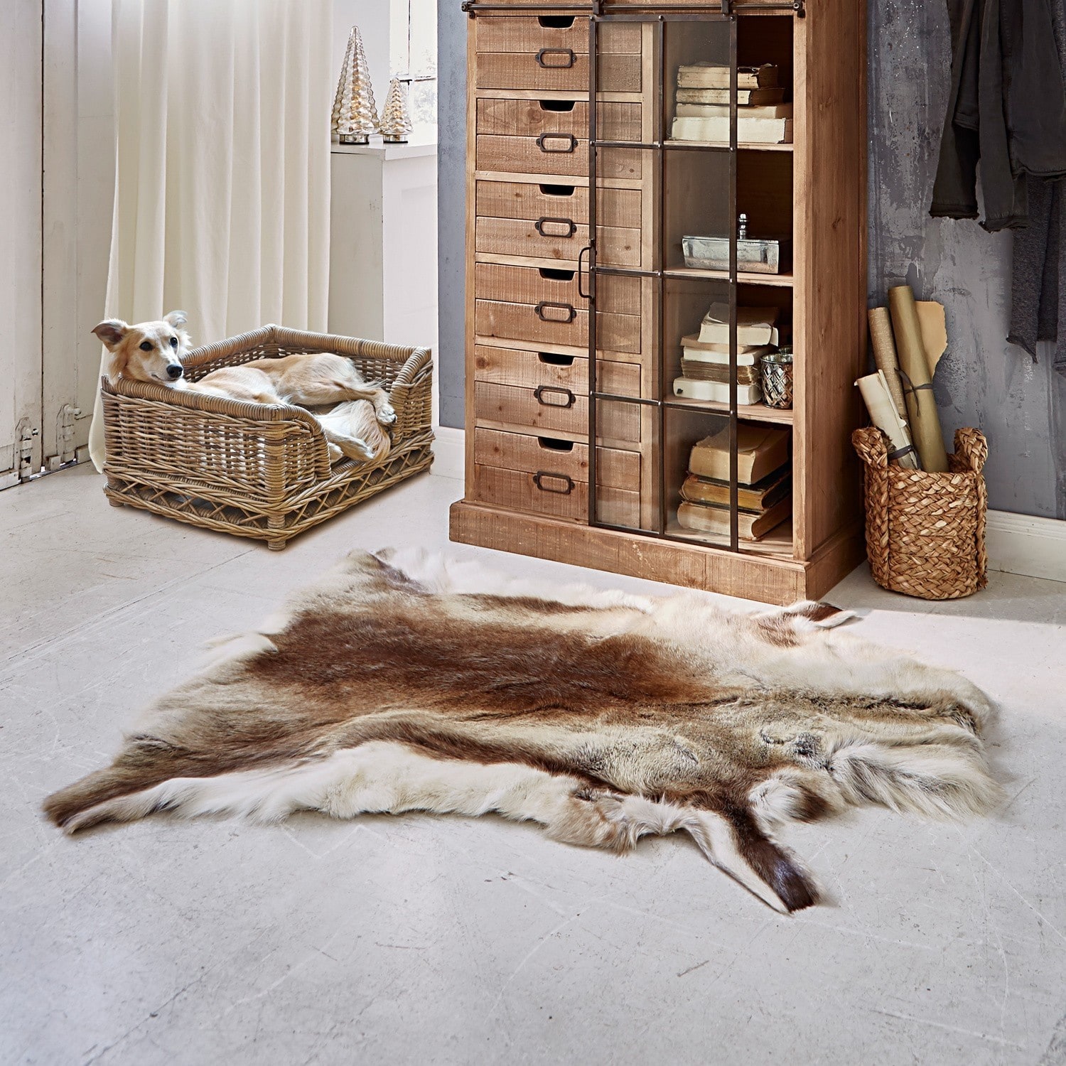 Naturfarbener braun-beiger Tierfell-Teppich auf hellem Boden neben Korb und Holzschrank im Raum