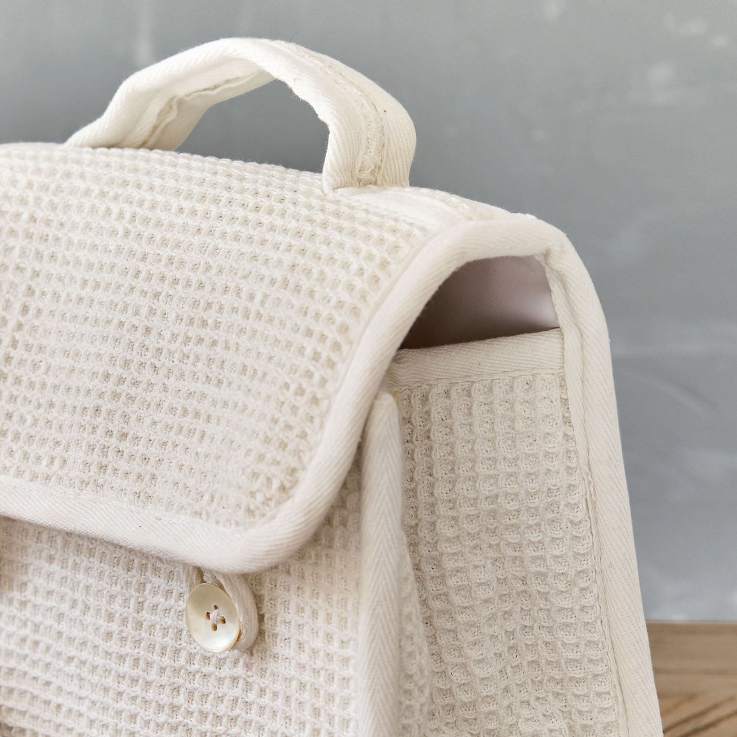Beige Tasche aus Waffelstoff mit Griff und Knopf, stilvolle Alltagstasche