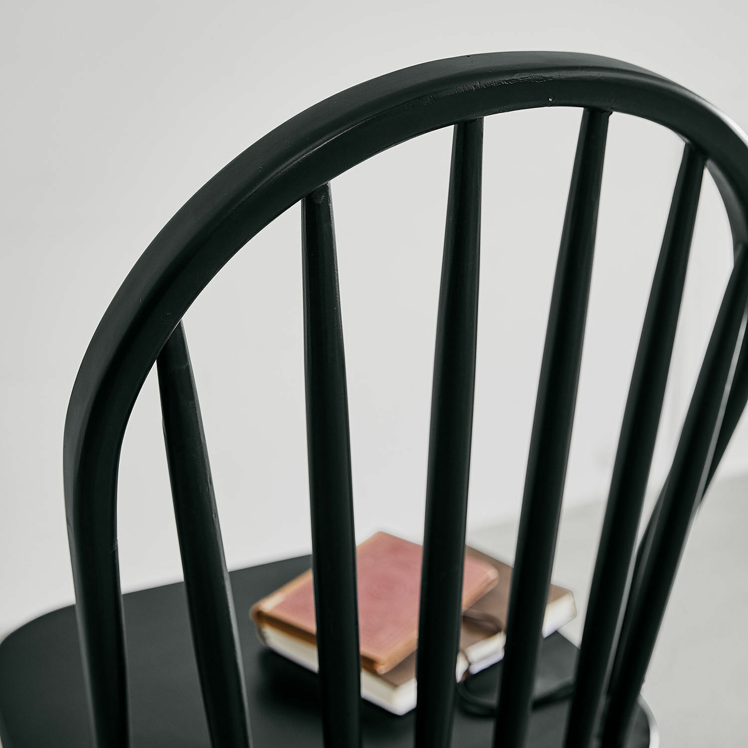 Schwarzer Holzstuhl mit senkrechten Stäben und Büchern auf dem Sitz, modernes Design