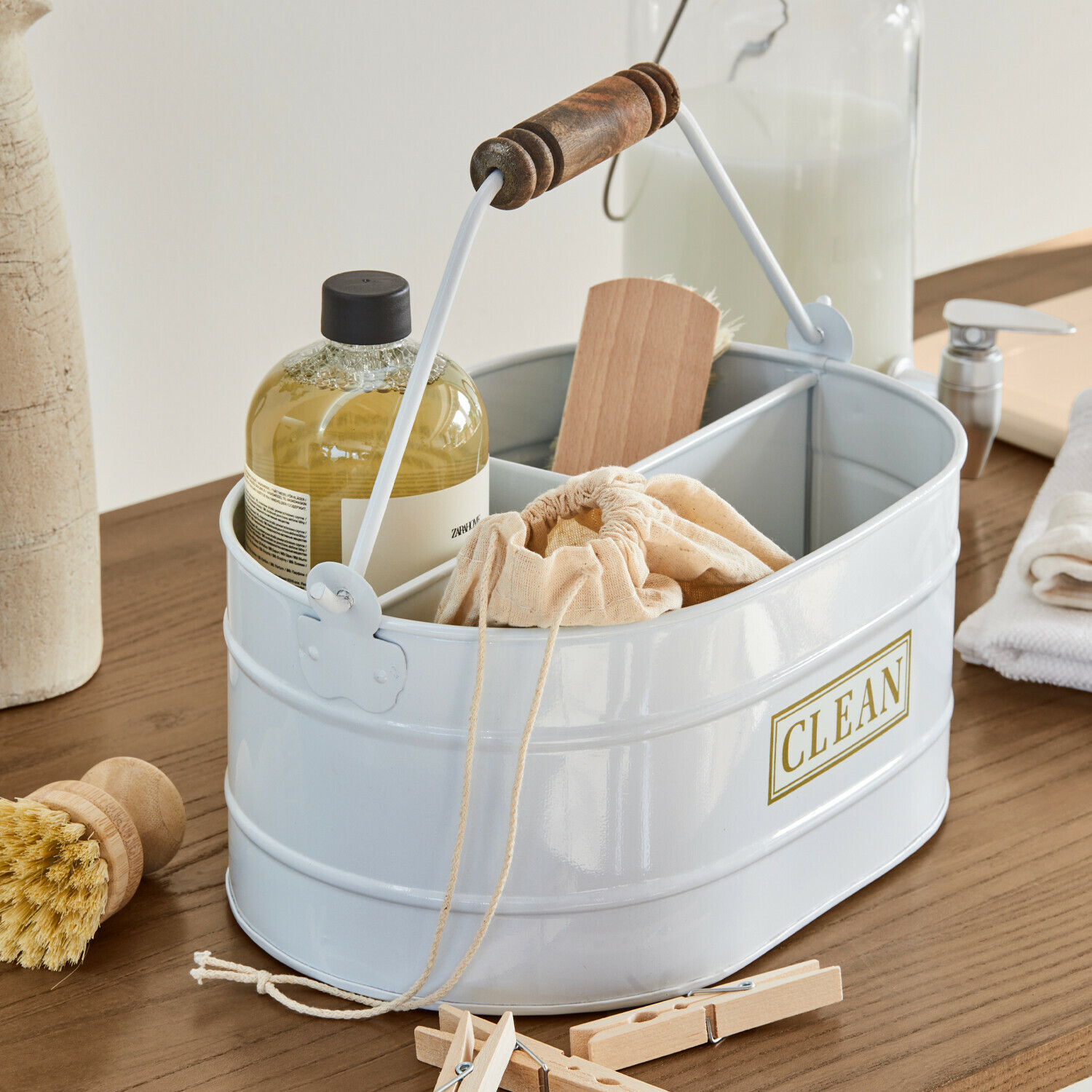 Weiße Metall-Organizer mit Holzgriff und Aufschrift CLEAN, gefüllt mit Reinigungsutensilien