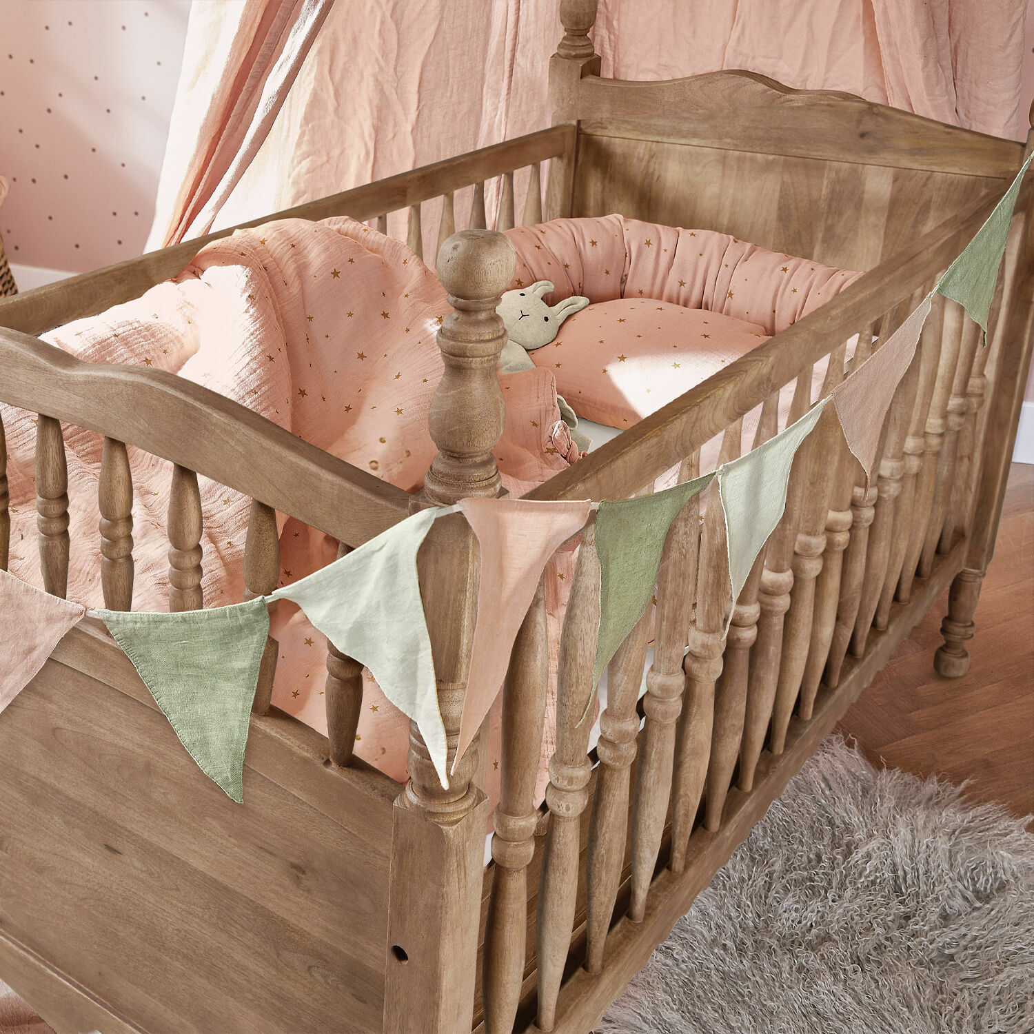 Kinderbett aus Holz mit rosa Sternen-Bettwäsche und dekorativer Wimpelkette im Kinderzimmer
