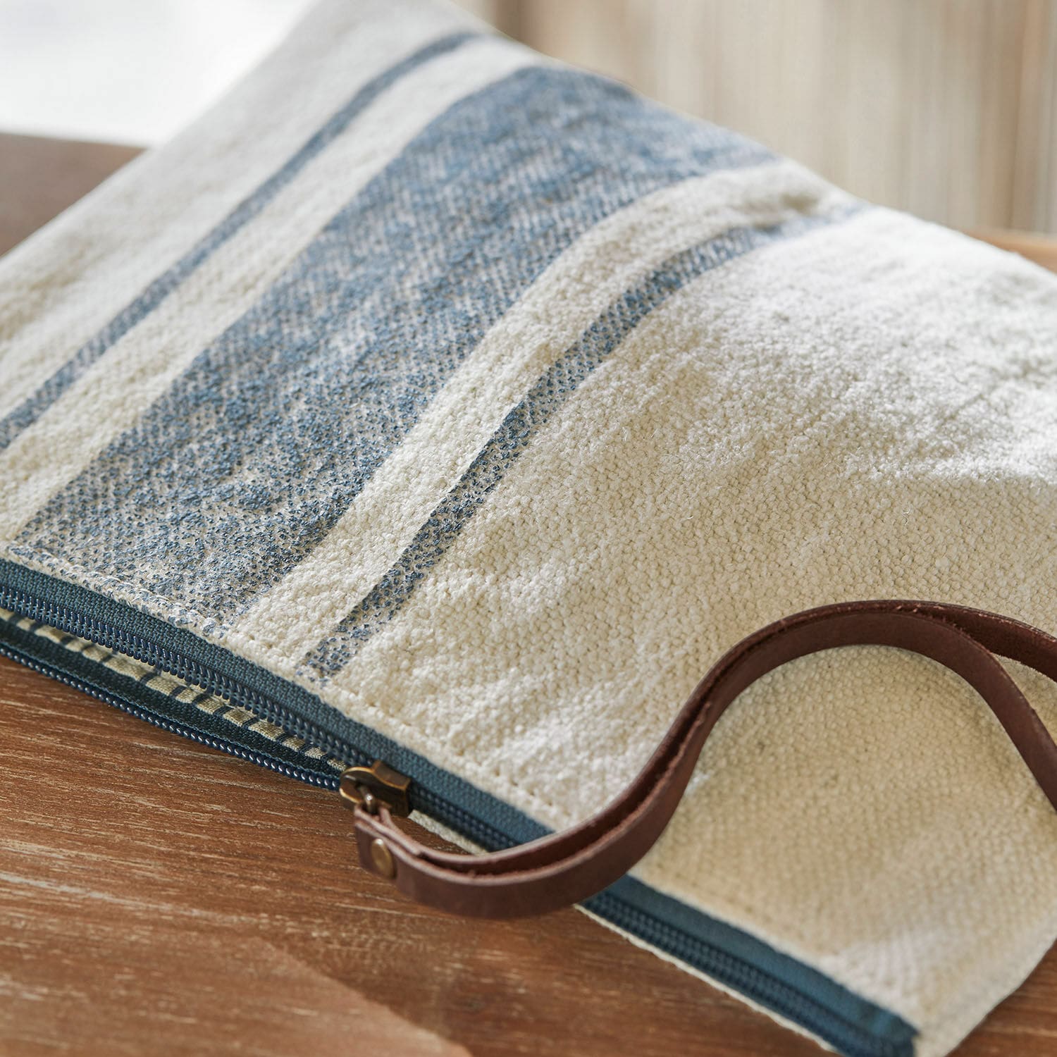 Beige-blaues Baumwoll-Kosmetiktäschchen mit Kunstlederriemen auf Holztisch