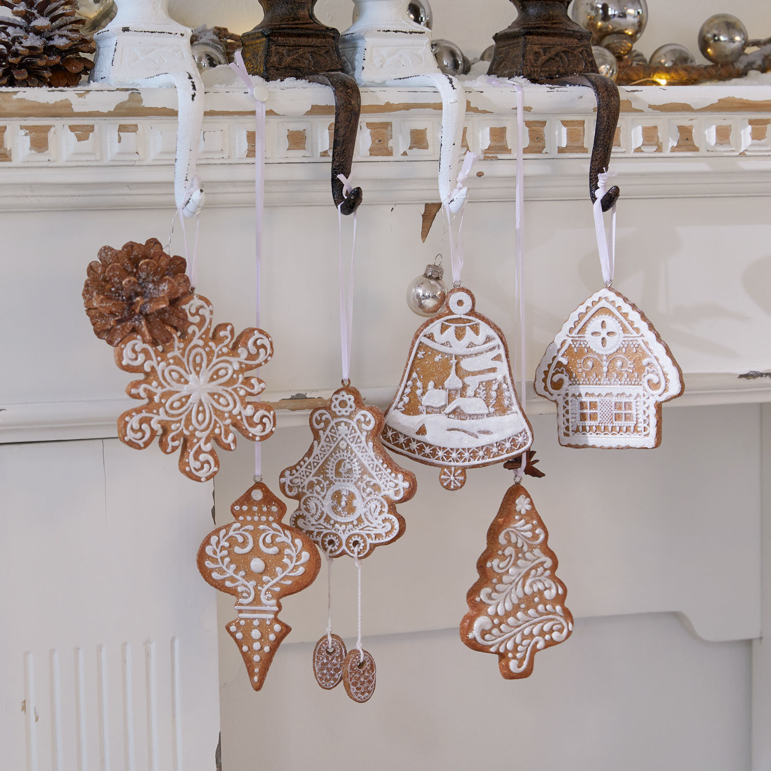 Set aus Lebkuchen-Weihnachtsanhängern mit weißer Glasur an Haken am Kamin, festliche Dekorationen