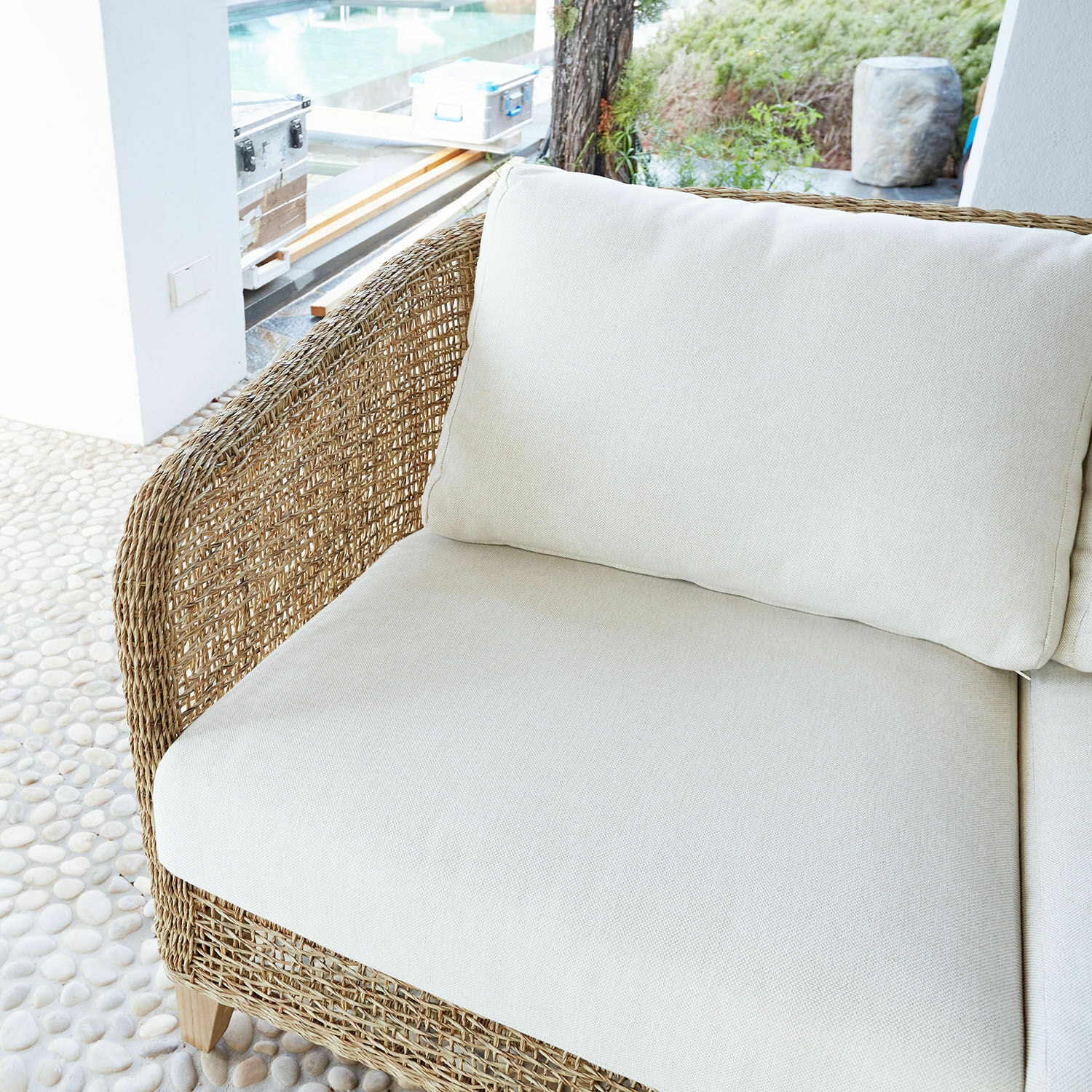 Rattansofa mit cremefarbenen Kissen im Außenbereich, gemütliches Gartenmöbel