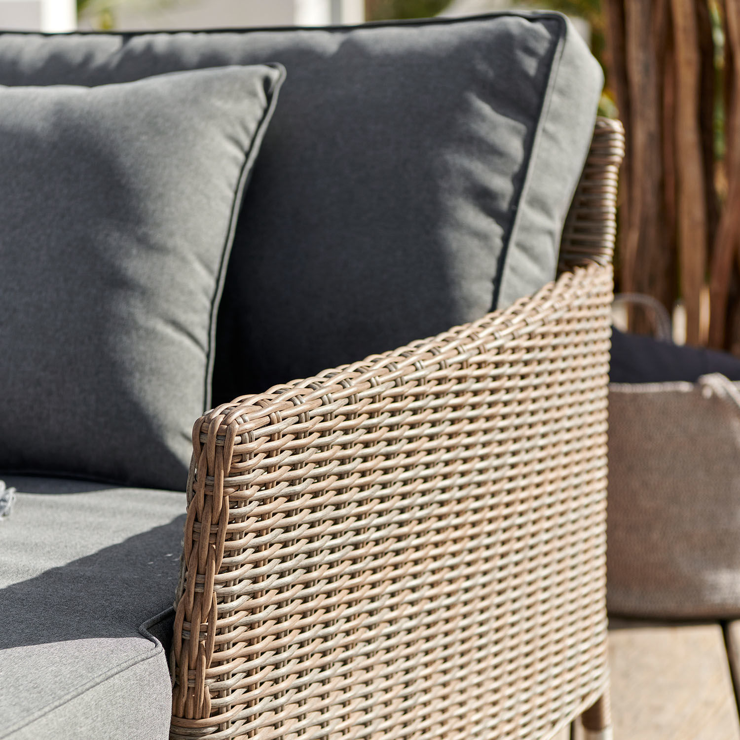 Gartensofa aus beigem Geflecht mit grauen Kissen, komfortables Terrassenmöbel