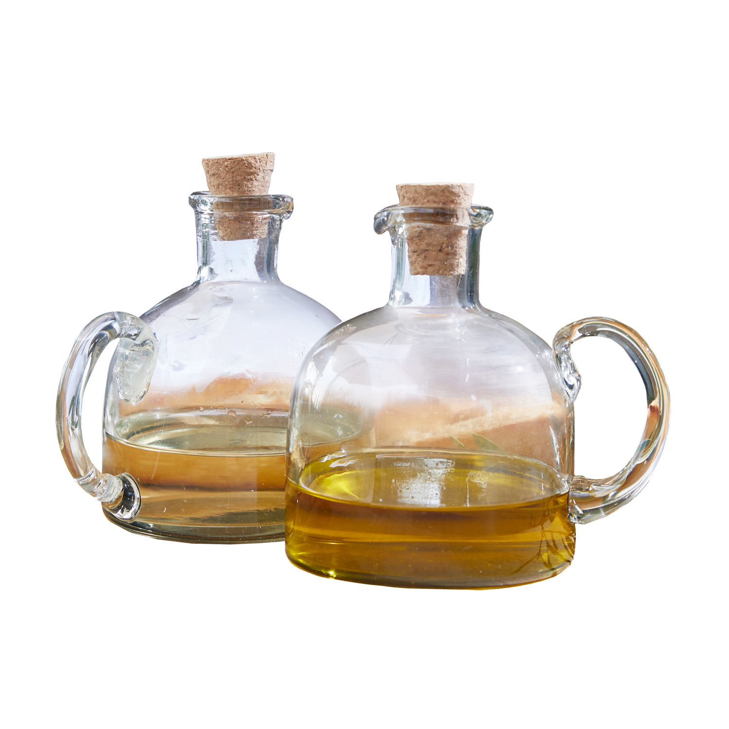 Zwei transparente Glasflaschen mit Korken und Griff, gefüllt mit goldenem Öl