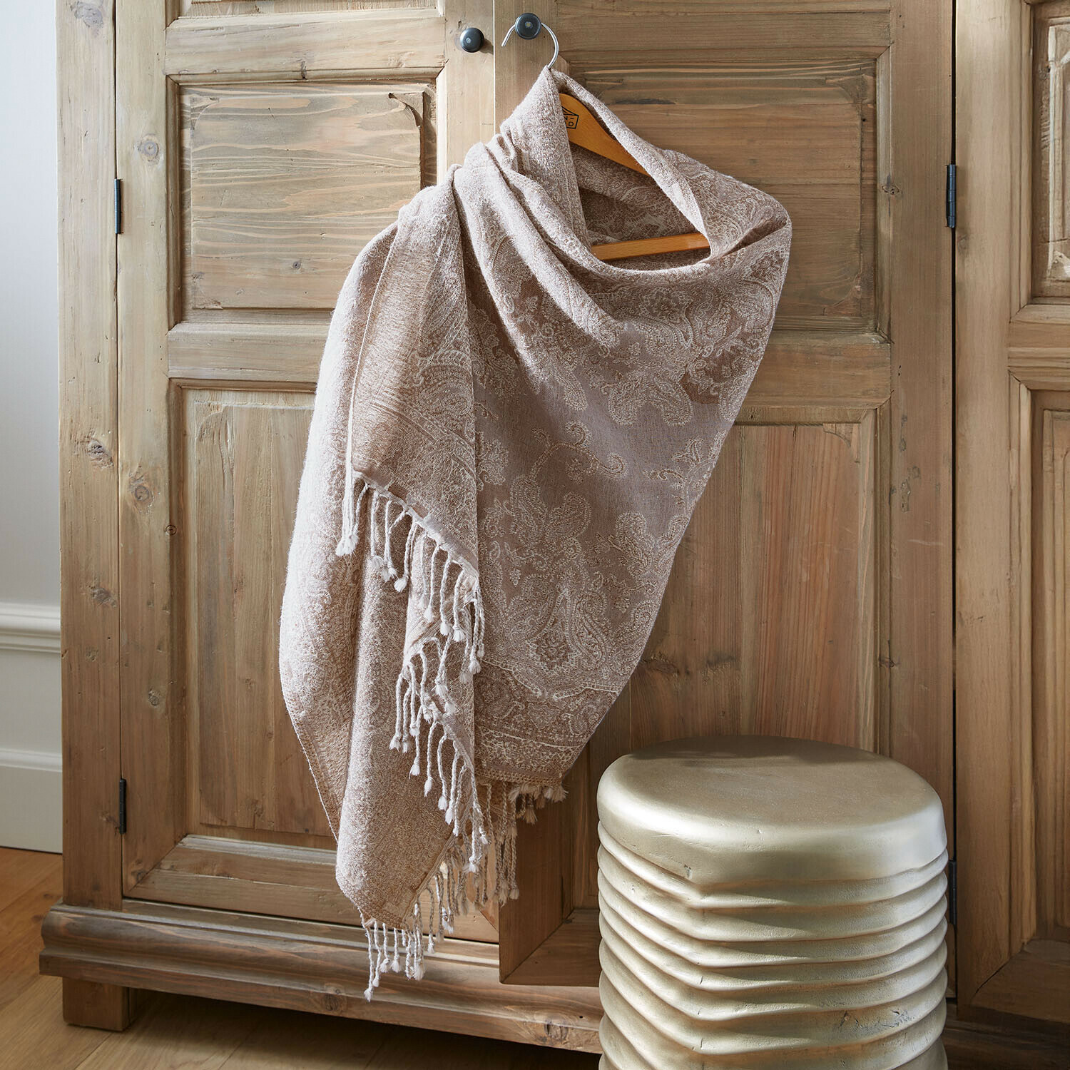 Beiger Schal mit Paisley-Muster und Fransen an Holzschrank, weiches Material, dekoratives Accessoire