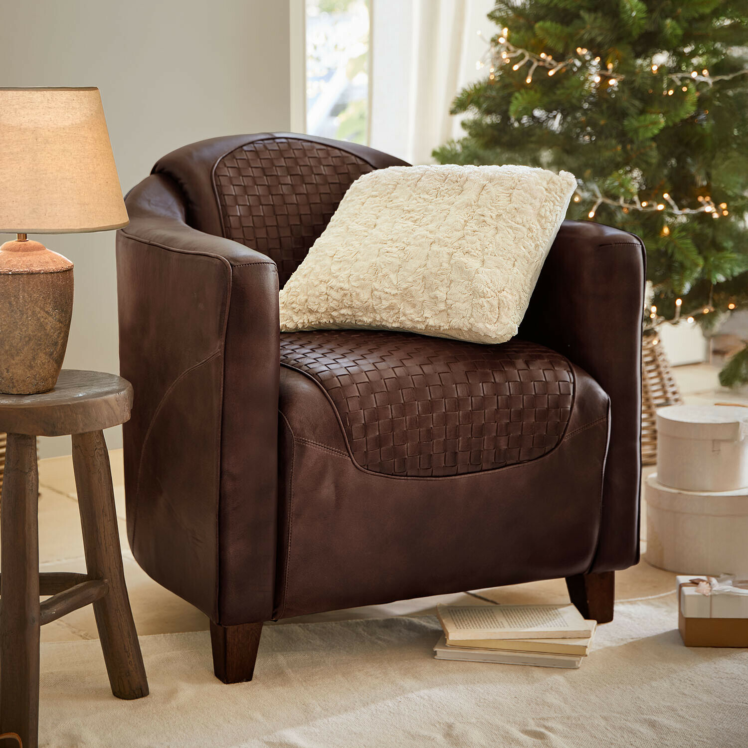Sessel Westerdales Brauner Ledersessel mit geflochtenem Sitz und cremefarbenem Kissen, gemütlich neben Lampe und Weihnachtsbaum
