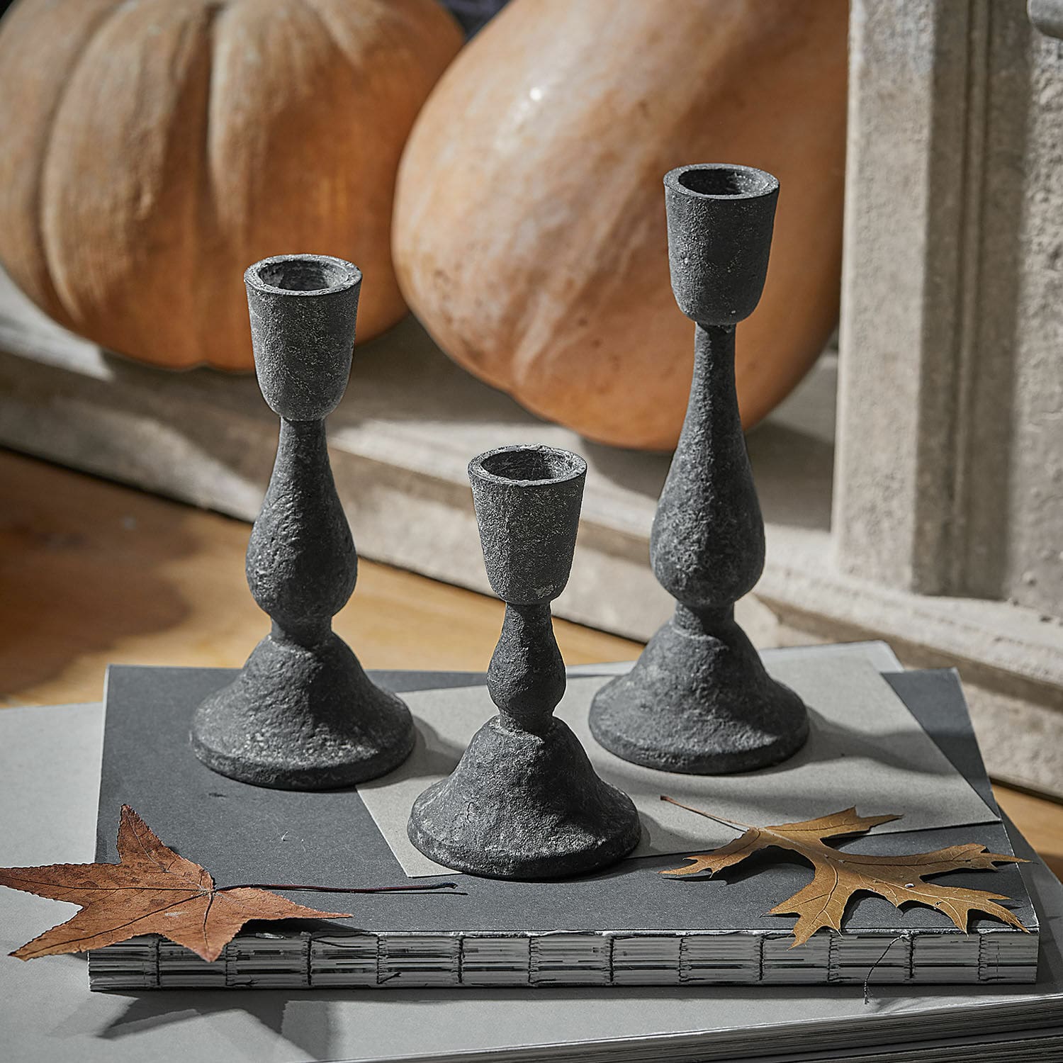 Set aus drei schwarzen Metall-Kerzenhaltern mit rustikalem Look auf herbstlichem Tisch