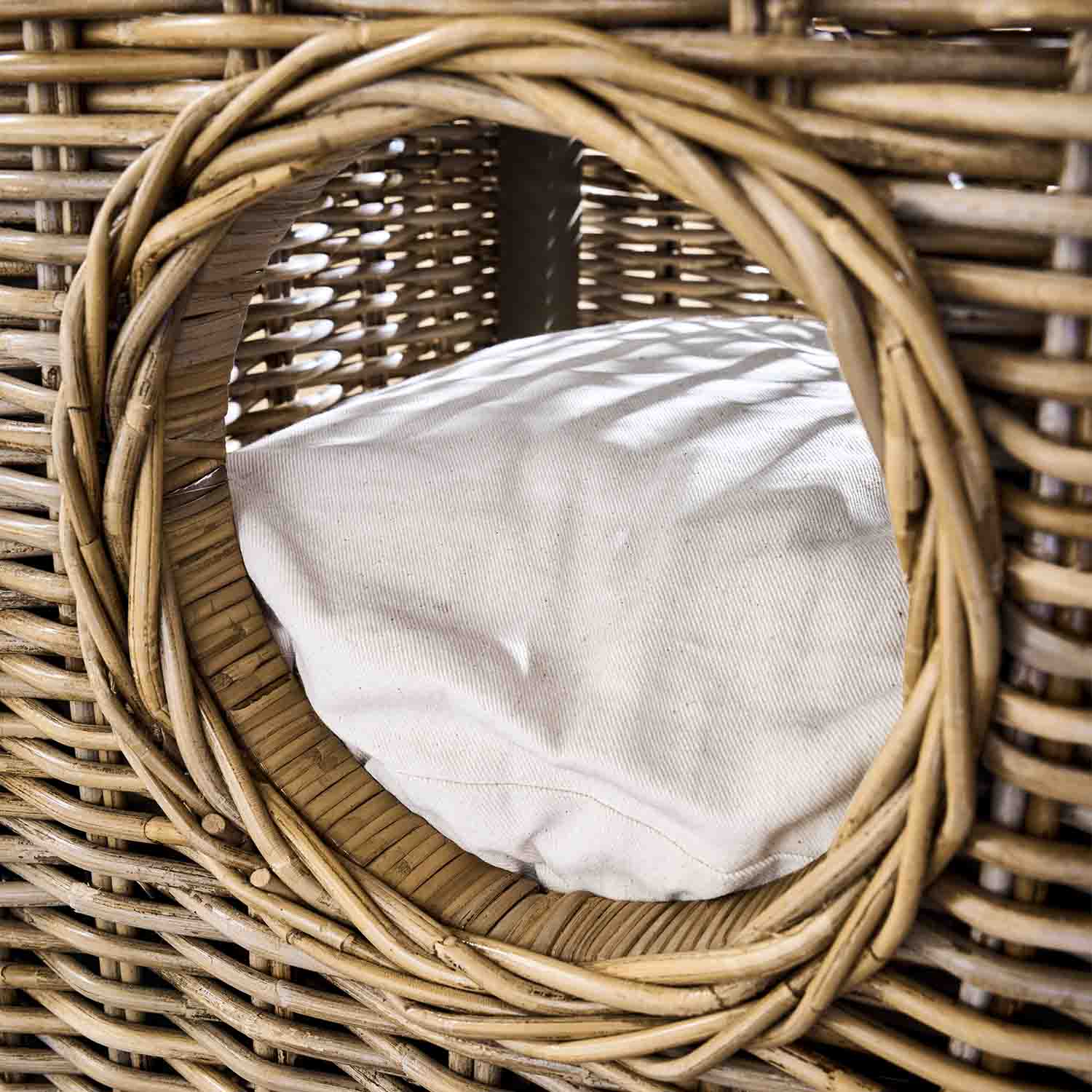 Runder Eingang eines Korbbetts aus Rattan mit weißem Kissen, natürlicher Farbton und Material