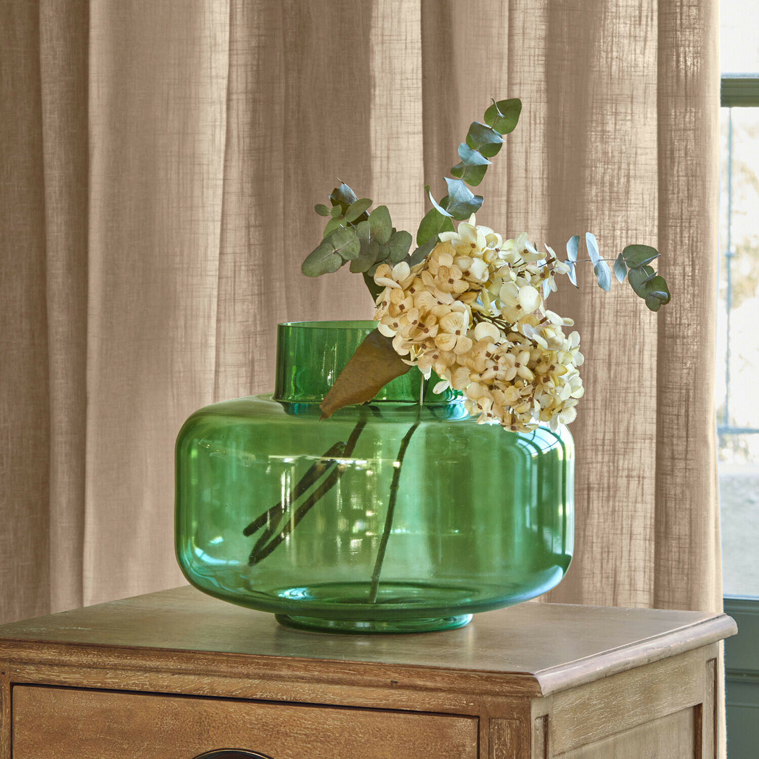 Vase Ésmarine Grüne Glasvase mit cremefarbenen Blumen auf Holztisch, stilvolle Wohnraumdekoration