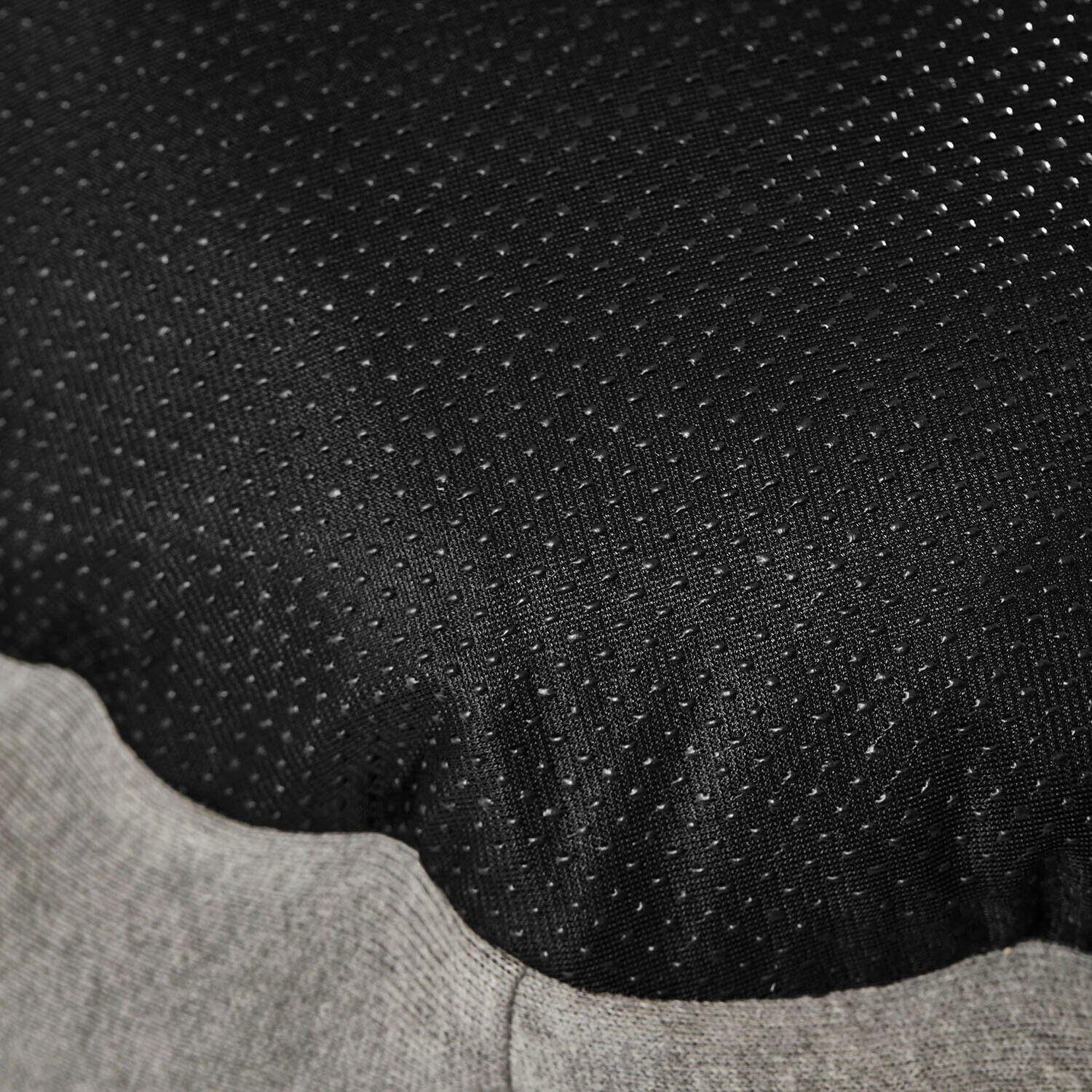 Schwarzer Stoff mit kleinen Noppen und grauem Strickabschluss, textile Struktur sichtbar.