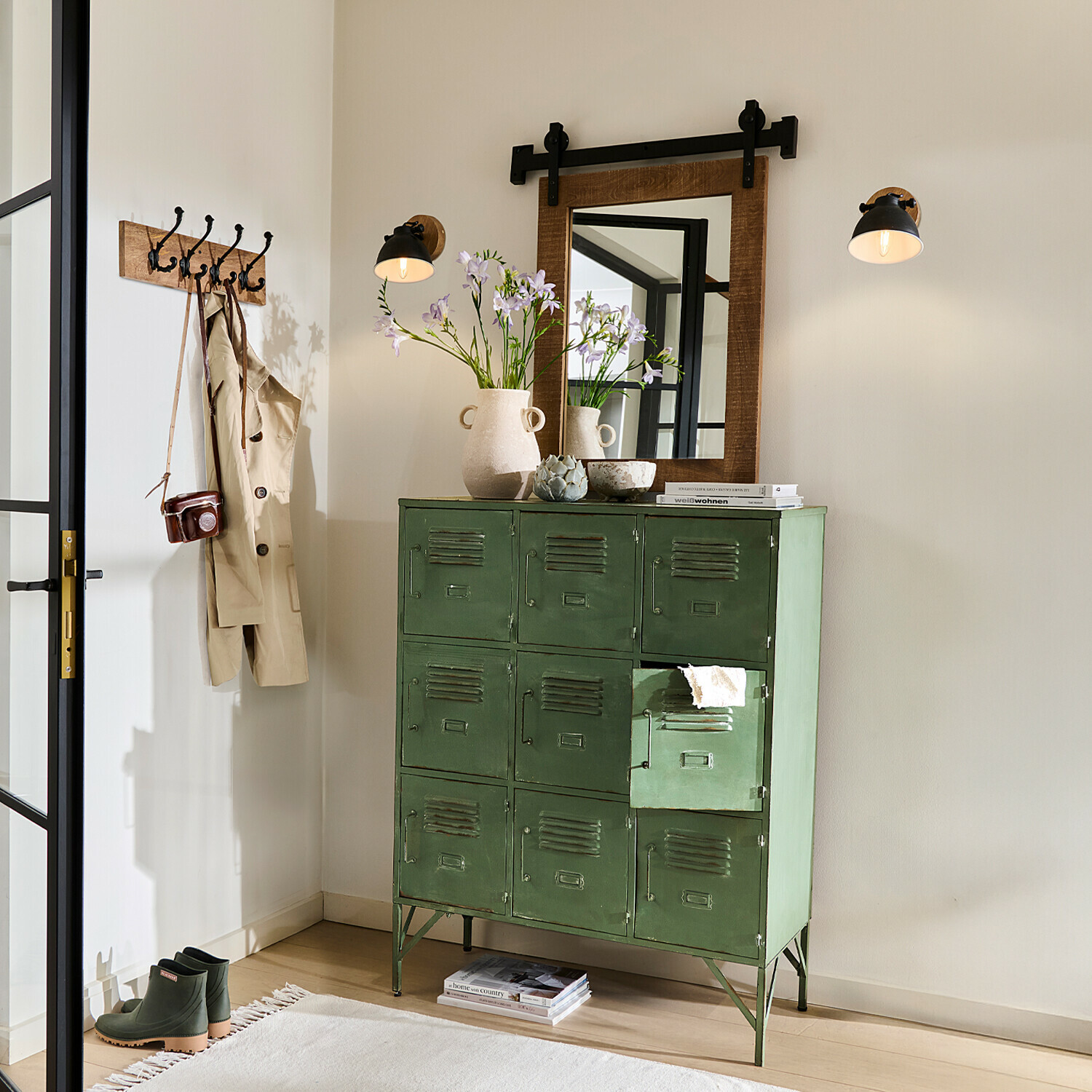 Grüner Metallschrank mit 12 Fächern im Vintage-Stil in hellem Raum mit Spiegel und Wandlampen