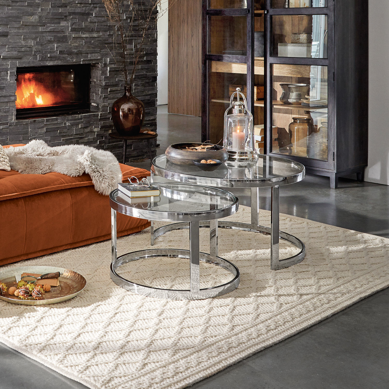 Zwei runde Couchtische aus Glas und Metall auf hellem Teppich in modernem Wohnzimmer