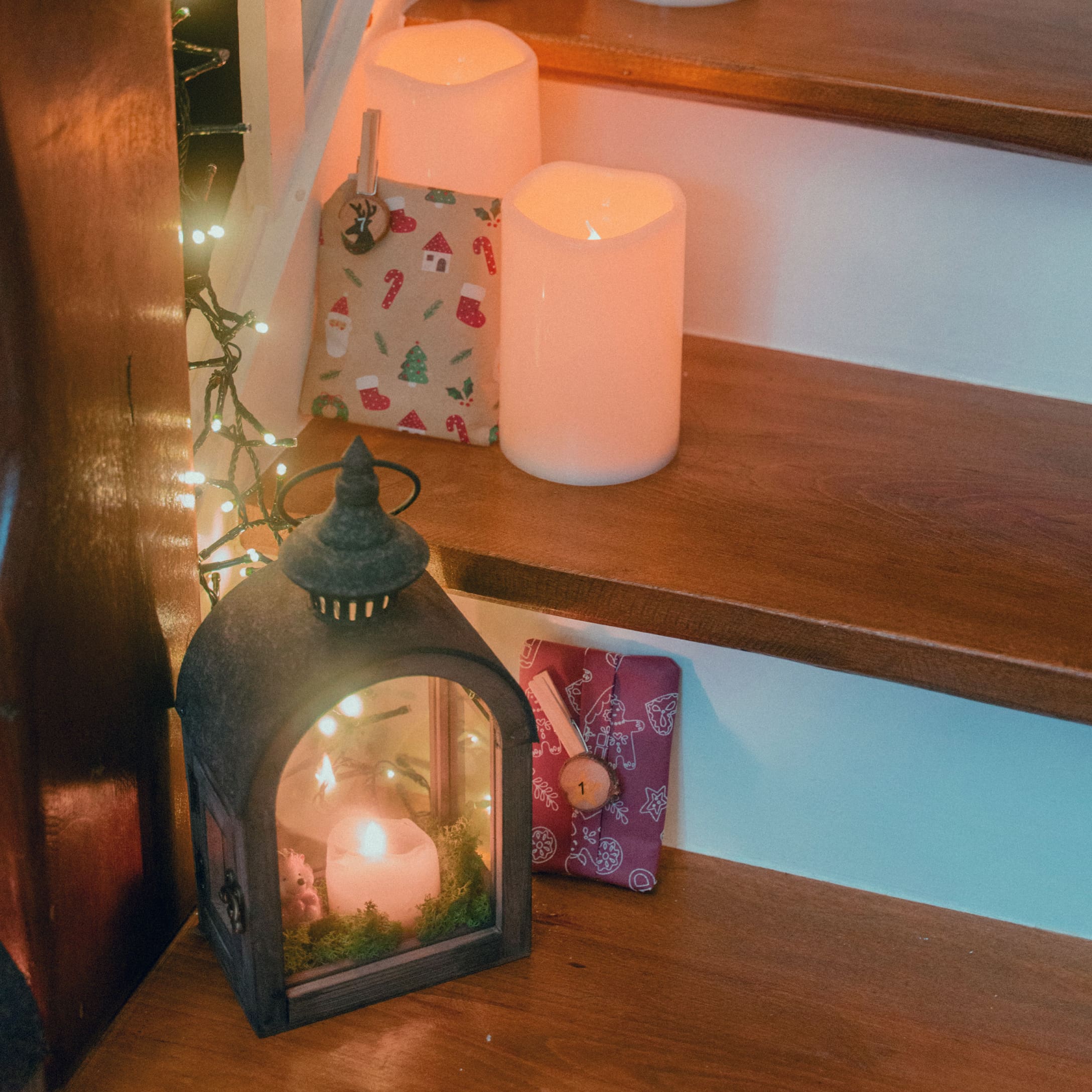 Metalllaterne mit Kerze und Weihnachtsgeschenken auf beleuchteten Holzstufen