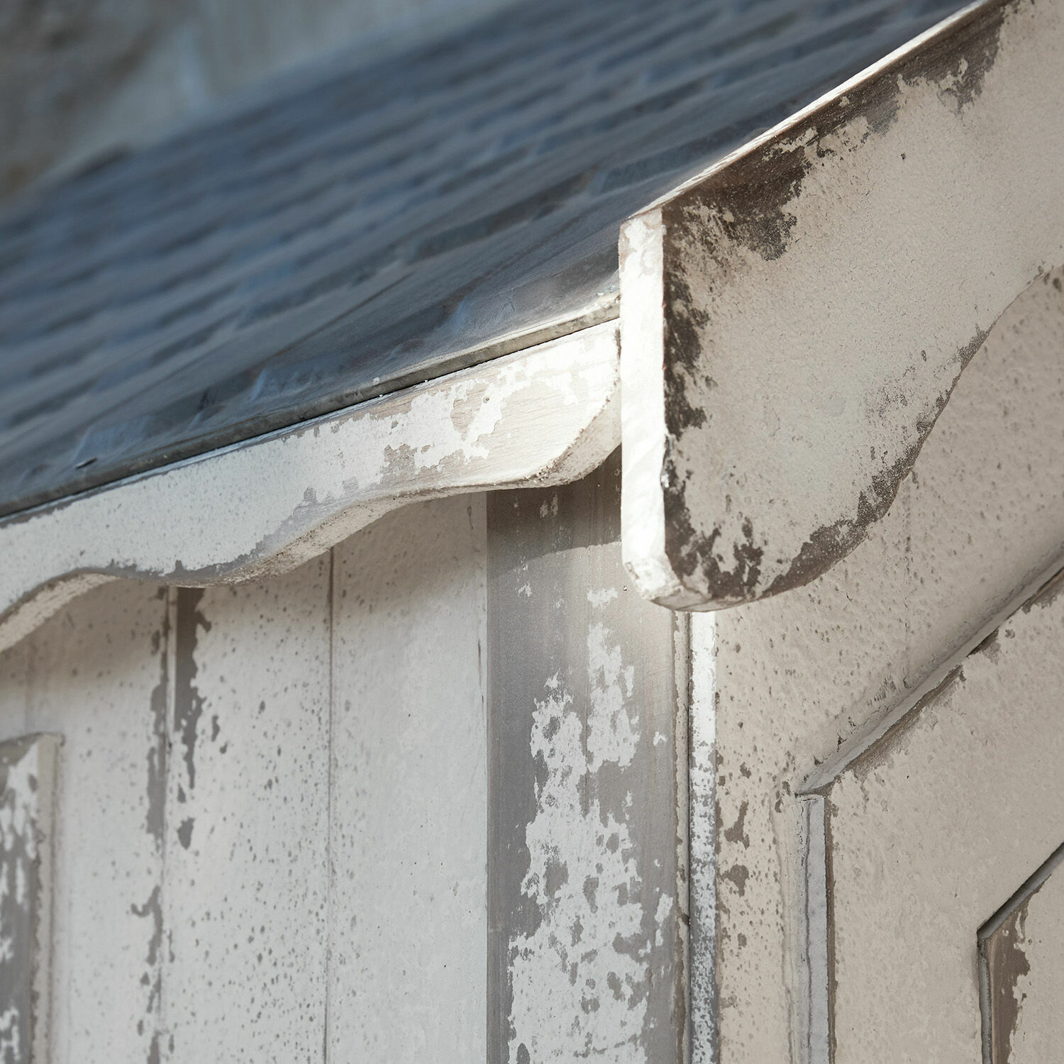 Nahaufnahme einer weiß gealterten Holzkonstruktion mit Metalldach, dekoratives Detail