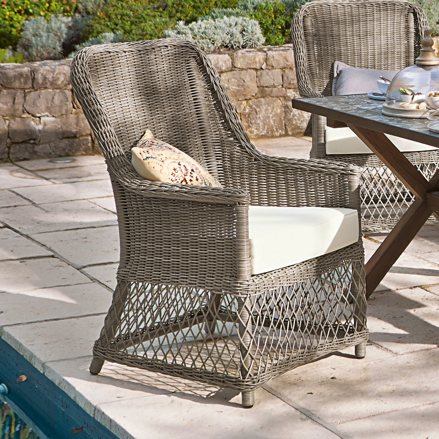 Gartenstuhl aus grauem Rattan mit weißem Polster, ideal für Terrassenmöbel und Entspannung