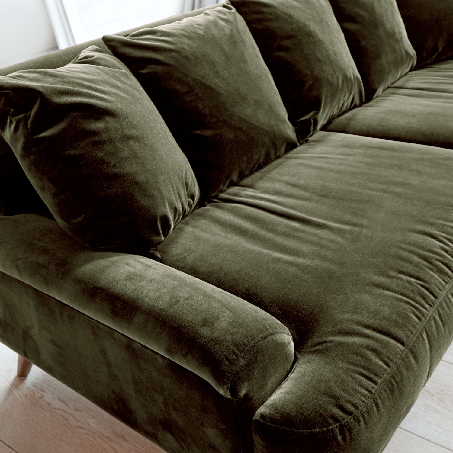 Grünes Samtsofa mit weichen Kissen und bequemen Armlehnen für Wohnzimmer