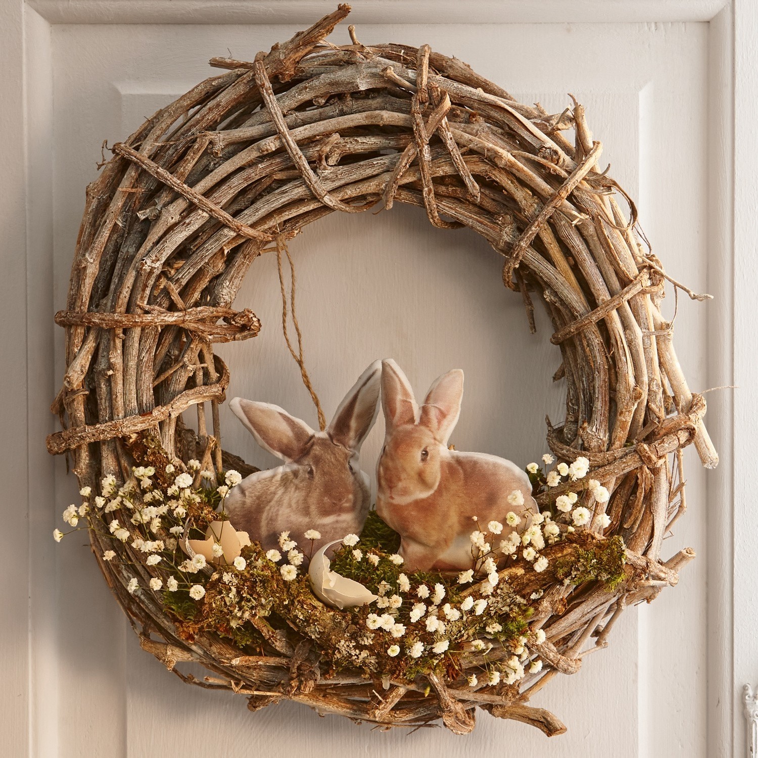 Kranz aus Zweigen mit Hasen, Eiern und weißen Blumen, Naturmaterial, Frühlingsdekoration
