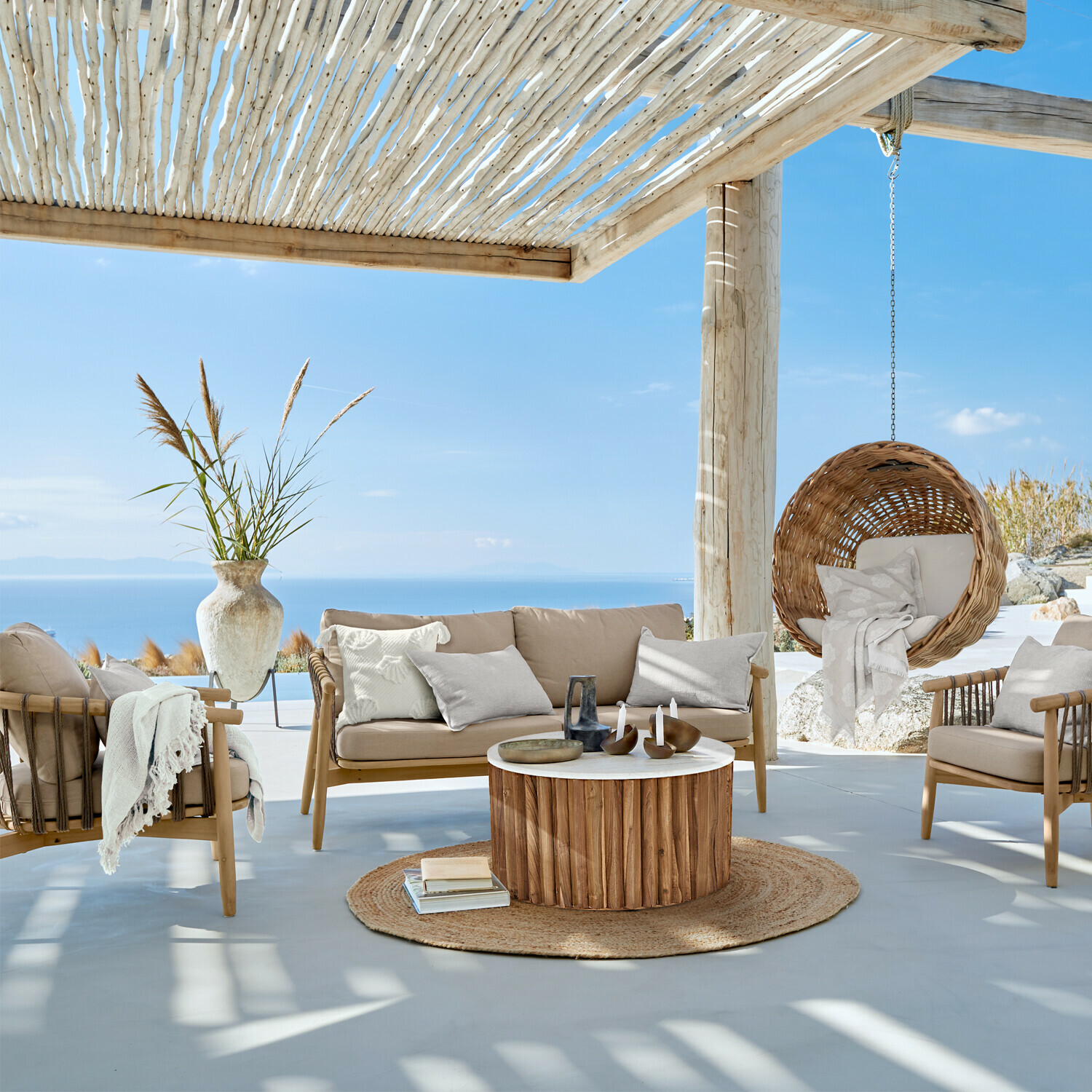 Gartenmöbel-Set aus Holz mit beigen Polstern, hängender Rattansessel auf Terrasse mit Meerblick