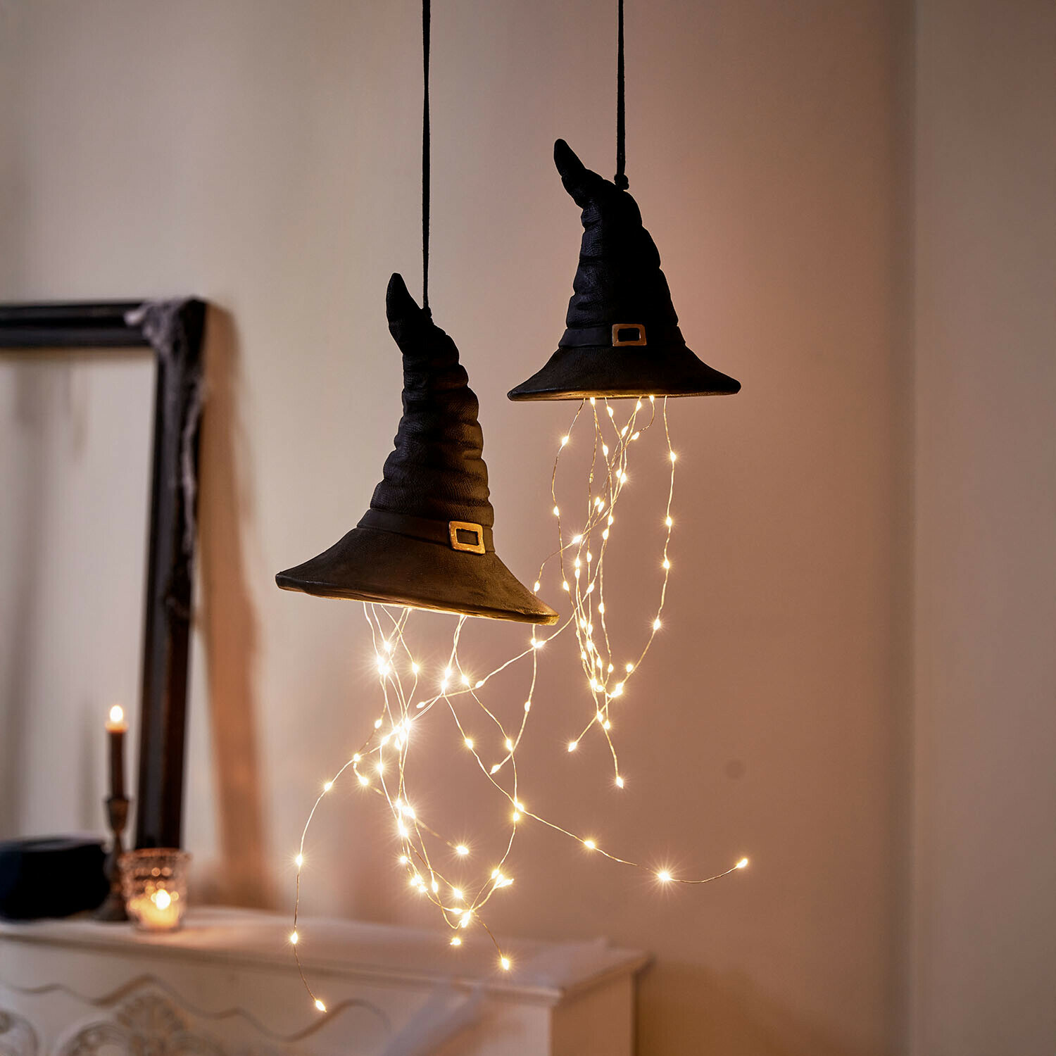 Dekorative schwarze Hexenhüte mit LED-Lichterketten, hängend in gemütlicher Halloween-Dekoration