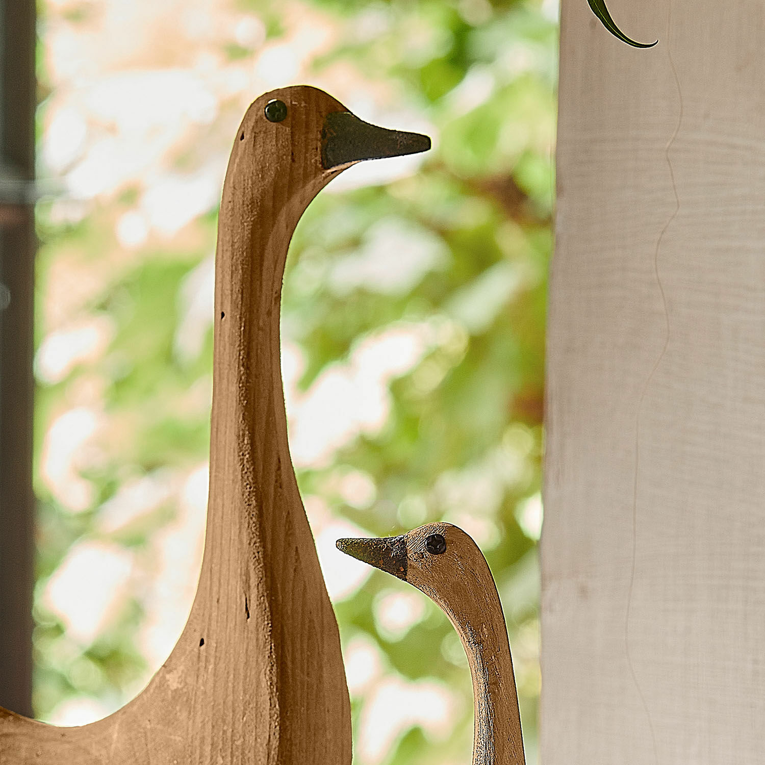 Holzdekorationen in natürlicher Farbe mit Vogelmotiv vor grünem Blätterhintergrund, Wohnaccessoire