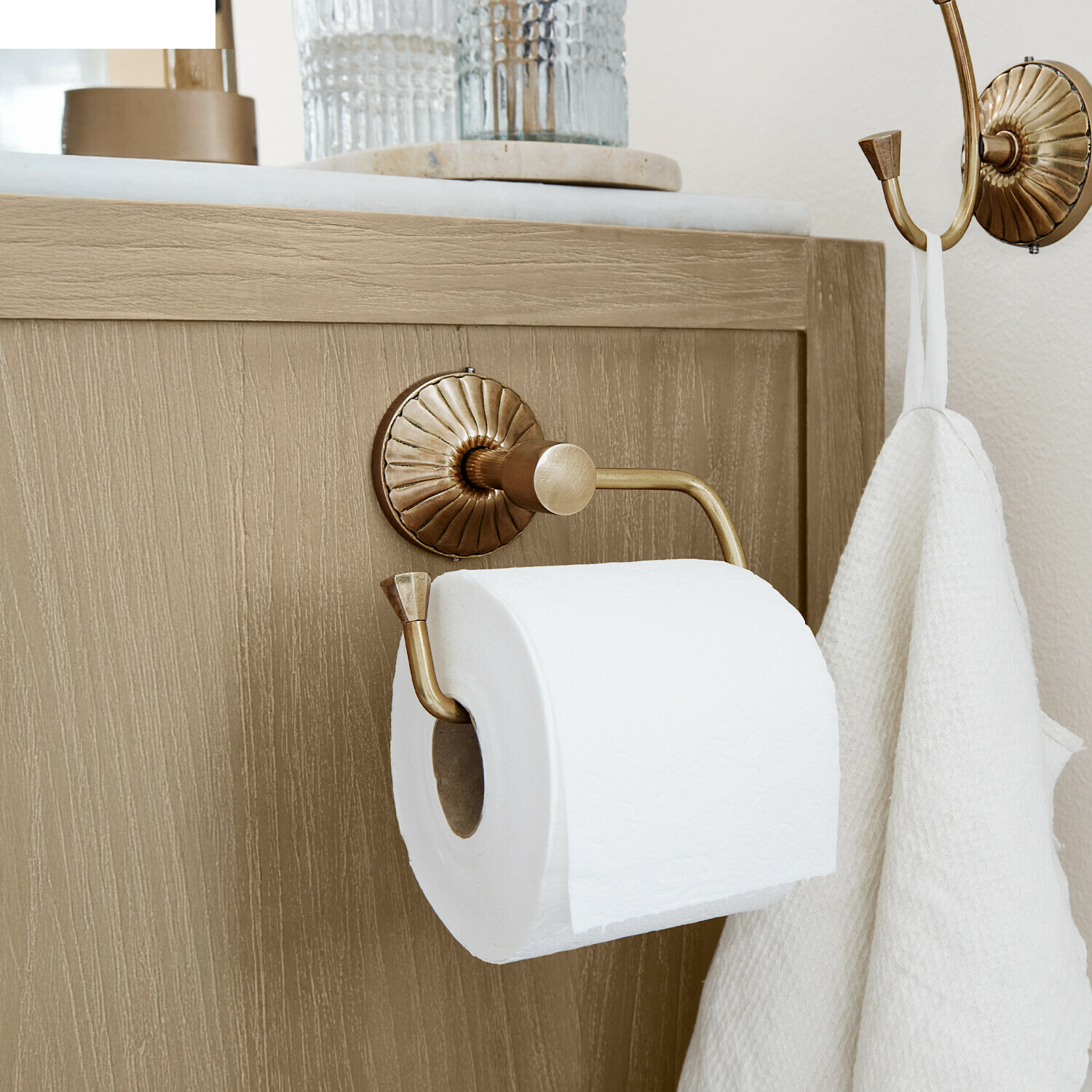 Toilettenpapierhalter Terling Messing Toilettenpapierhalter mit Haken und weißem Handtuch an hellem Holzschrank