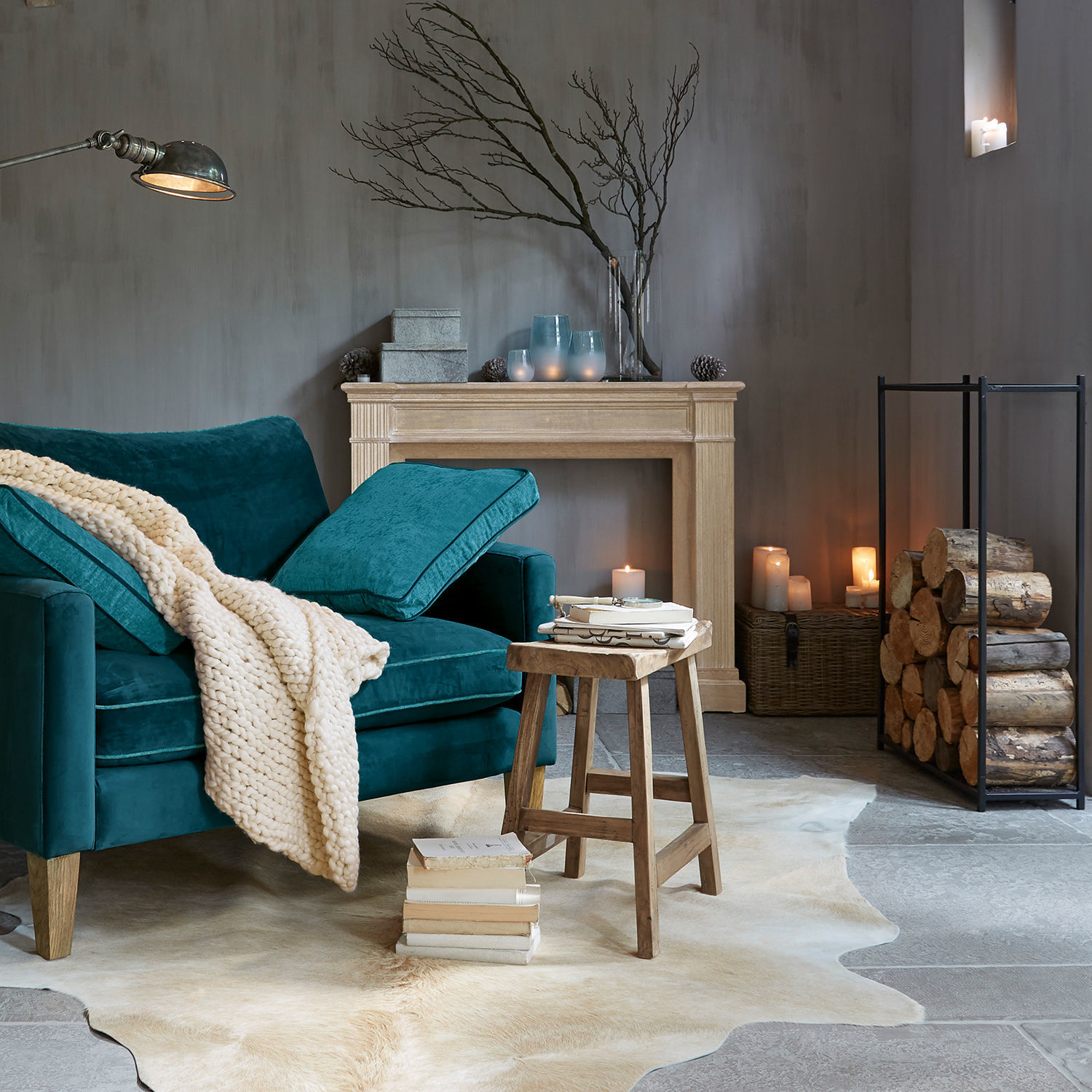 Türkisfarbiges Samtsofa mit cremefarbenem Strickplaid und Holzschemel auf Fellteppich