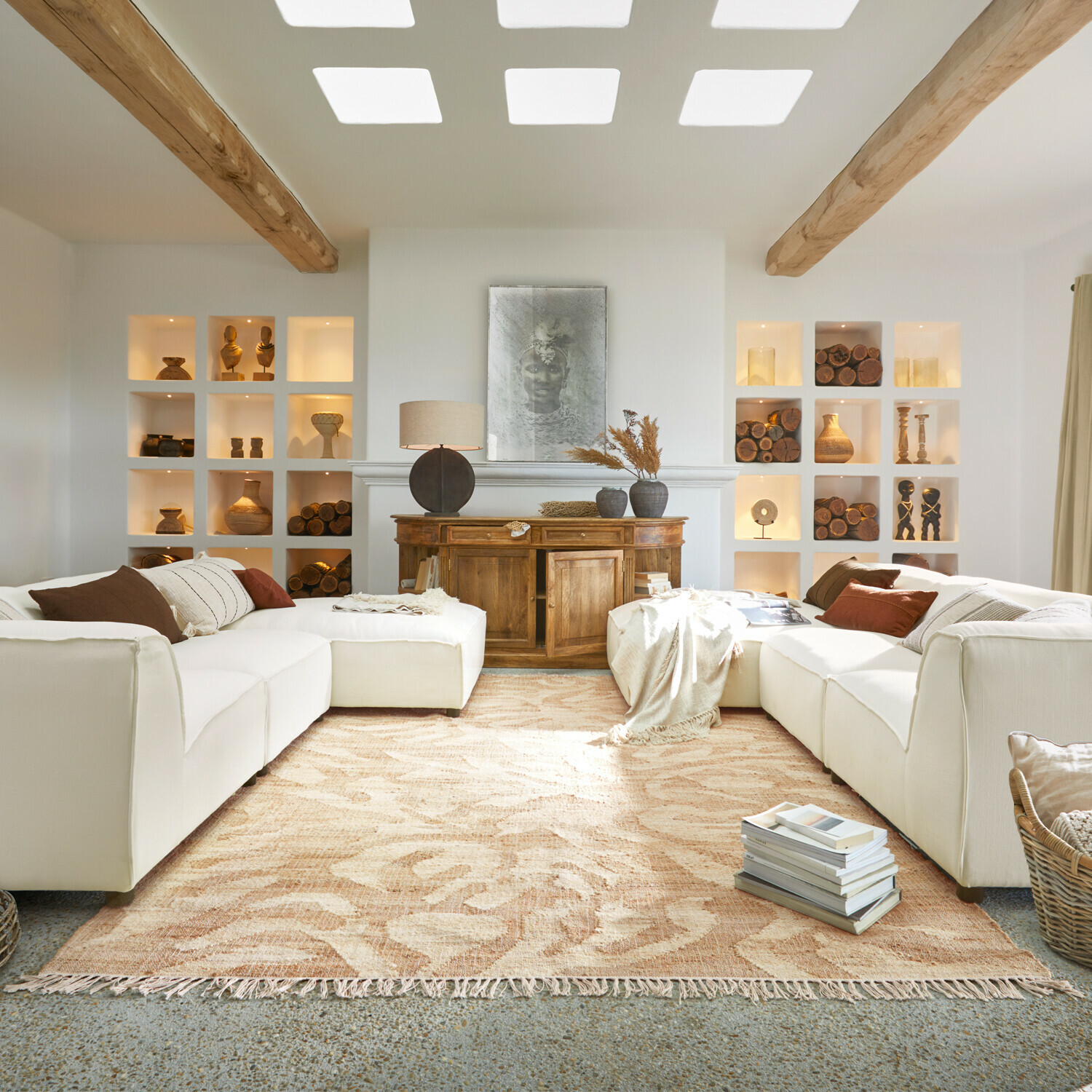 Teppich Marsetta Gemütliches Wohnzimmer mit weißem Sofa, Holzkommode, Holzdekorationen und beigem gemustertem Teppich