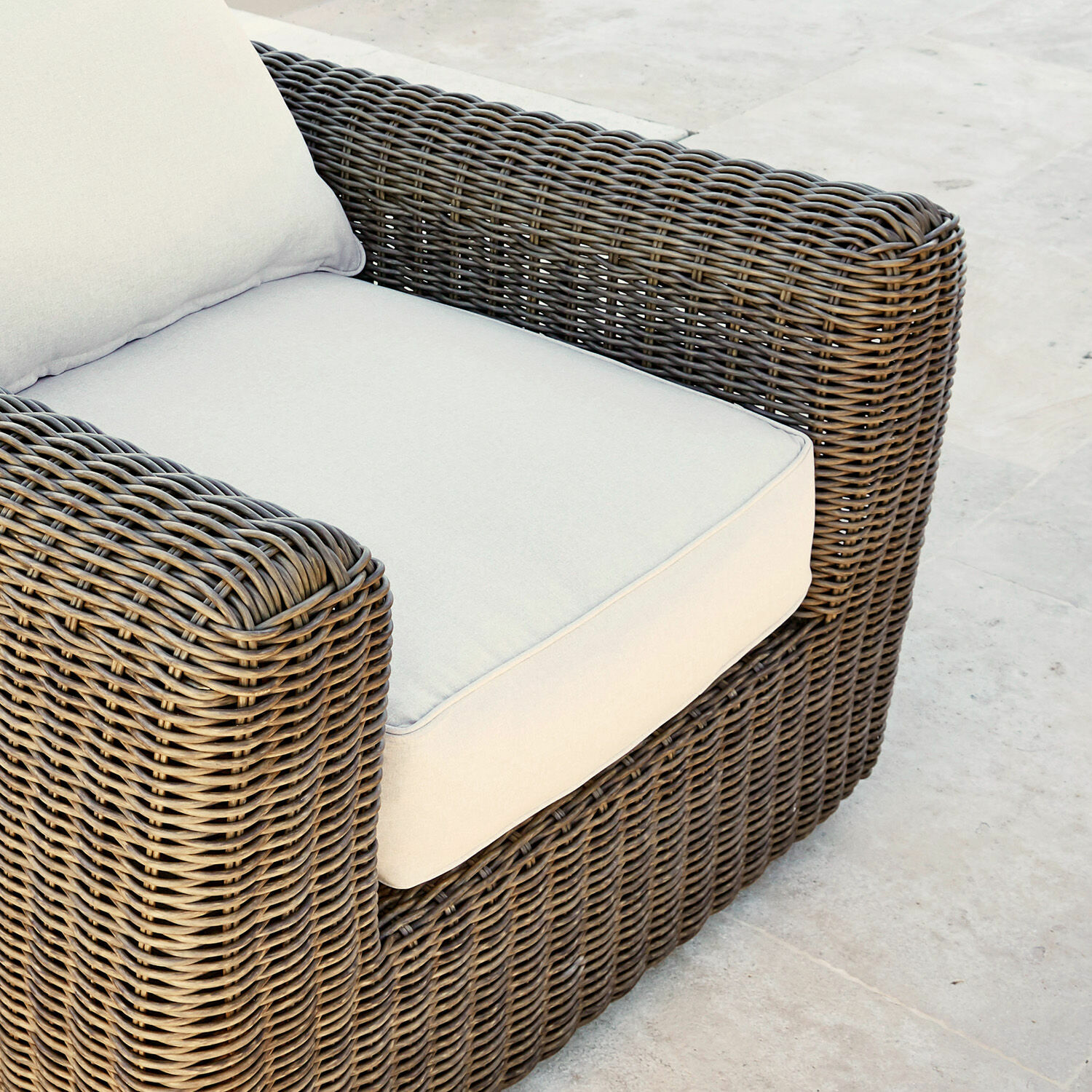 Brauner Geflecht-Sessel mit hellbeigem Kissen, bequemer Outdoor-Möbelstuhl mit Polster