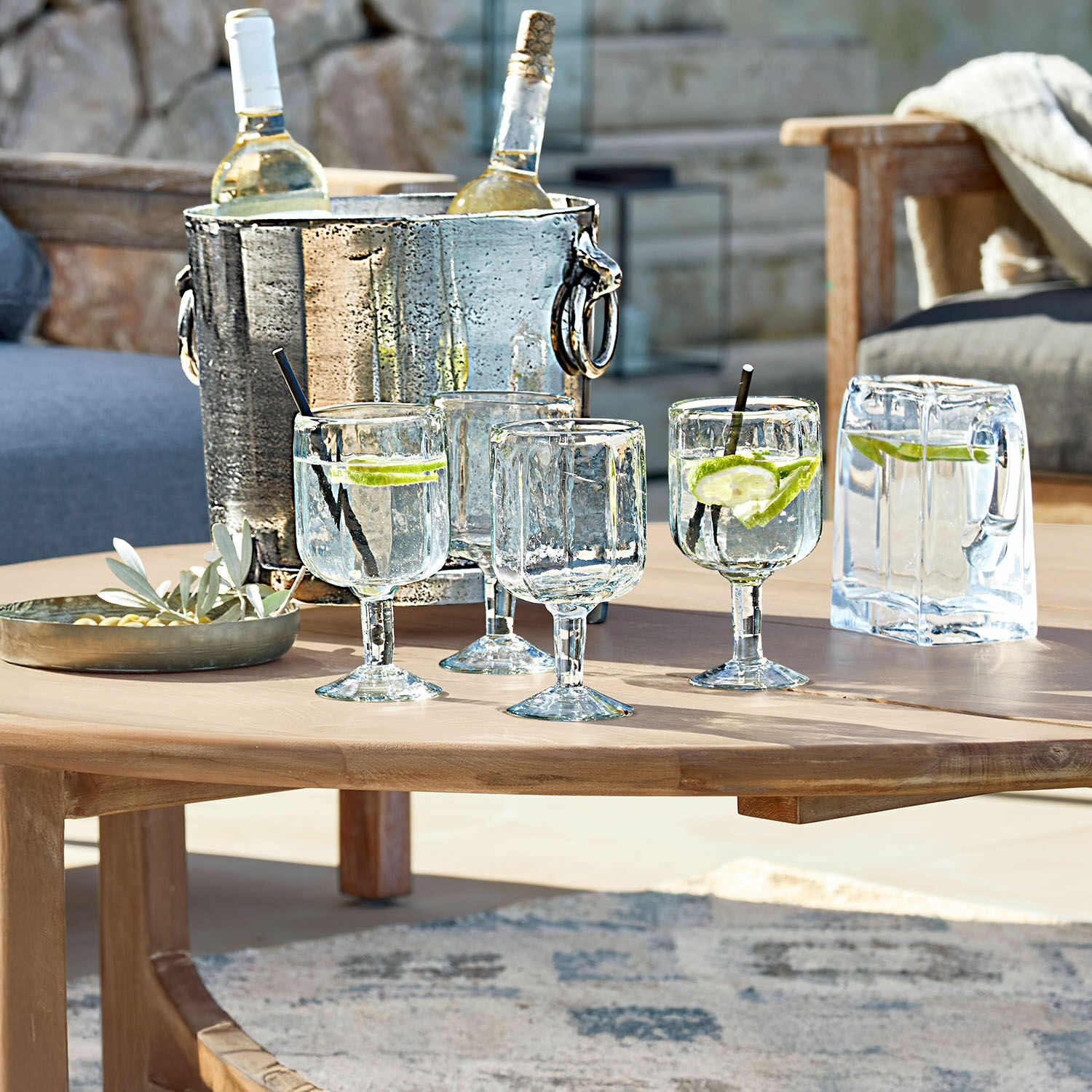 Gläser aus Glas mit Wasser und Limette auf Holztisch mit Metall-Weinkühler