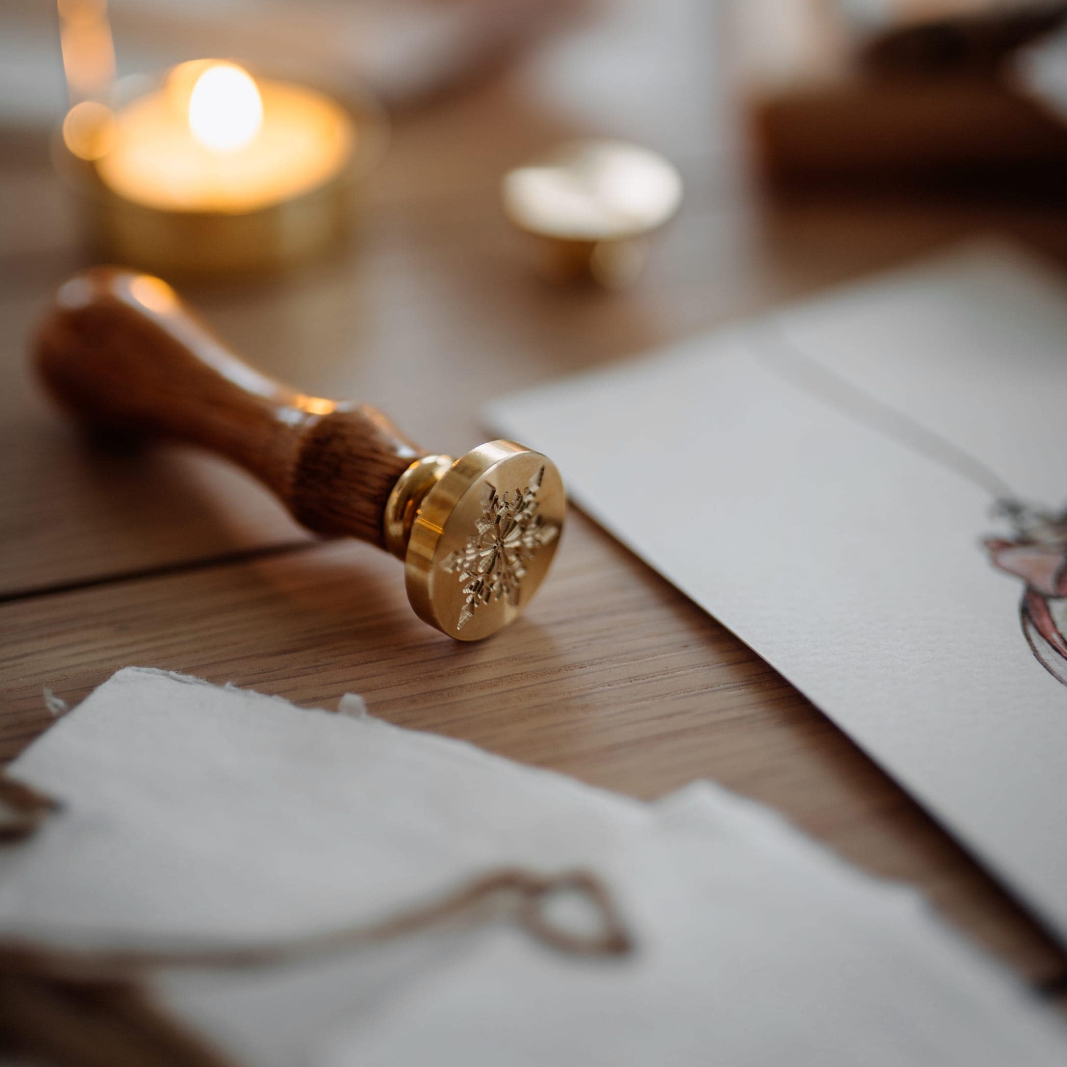 Siegelstempel aus Messing und Holz mit Schneeflockenmotiv auf Holztisch zum Geschenkverpacken