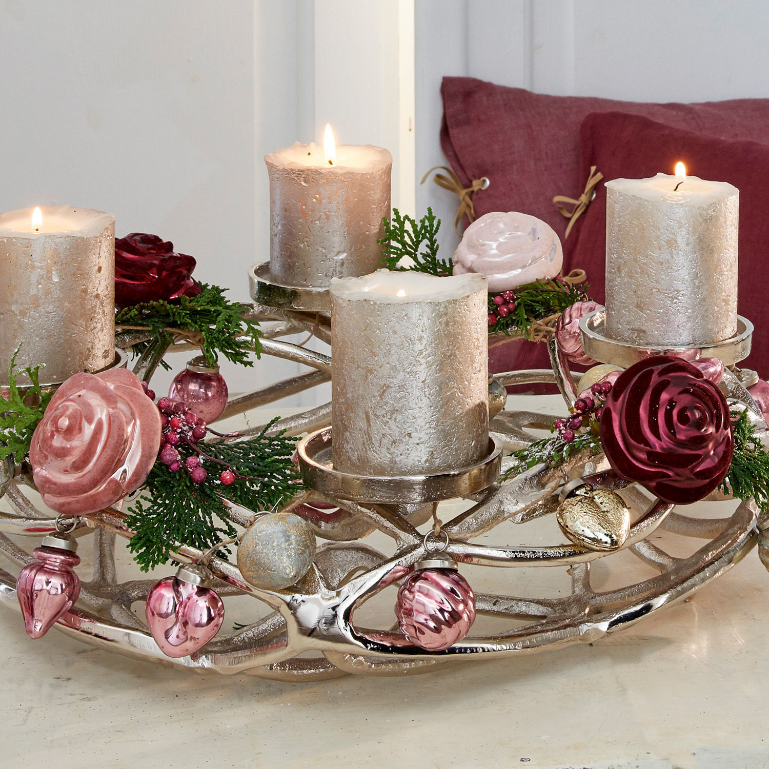 Adventskranz aus silbernem Metall mit vier silbernen Kerzen und rosa Blumenornamenten