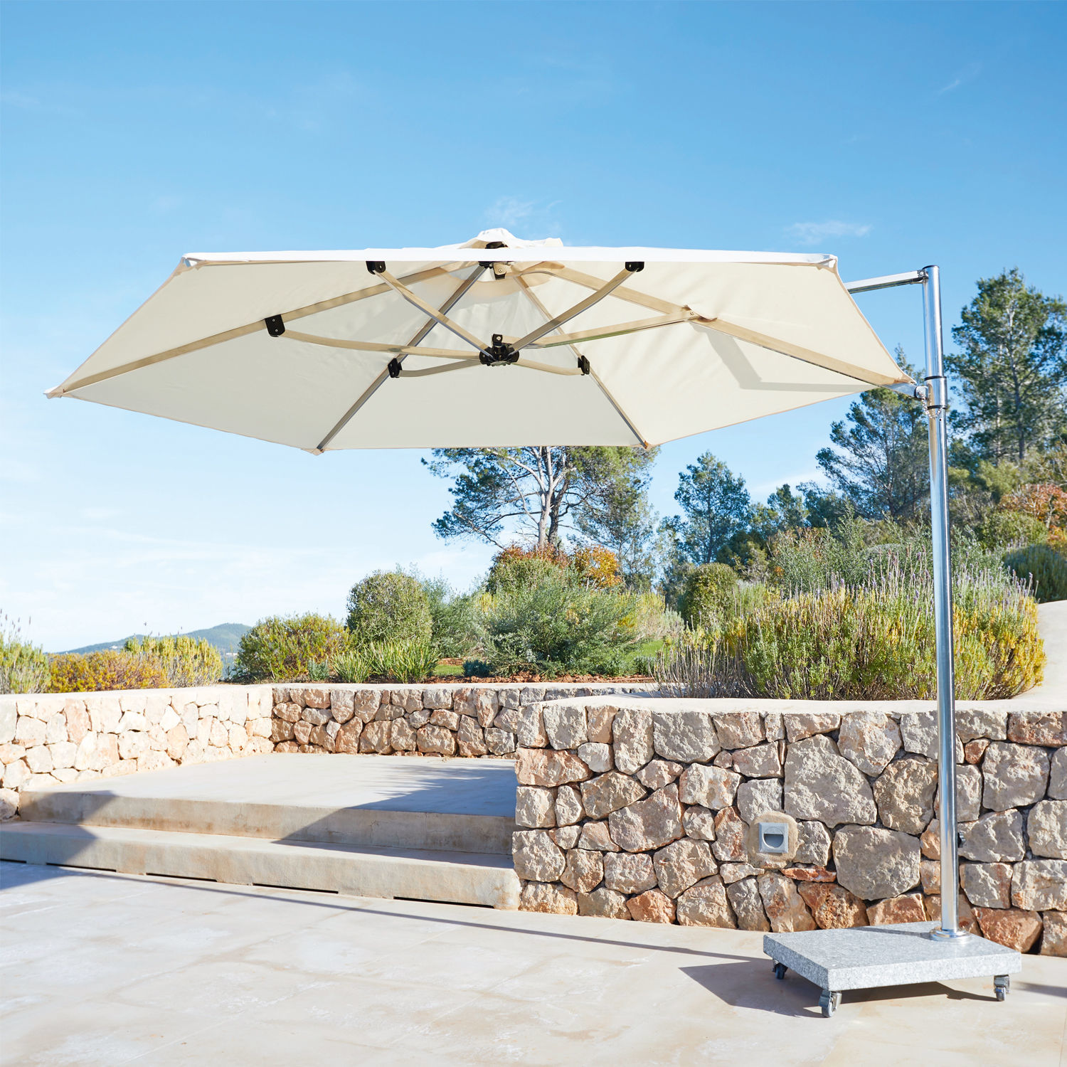 Großer weißer Gartenschirm mit Metallgestell und steinerner Basis auf sonniger Terrasse