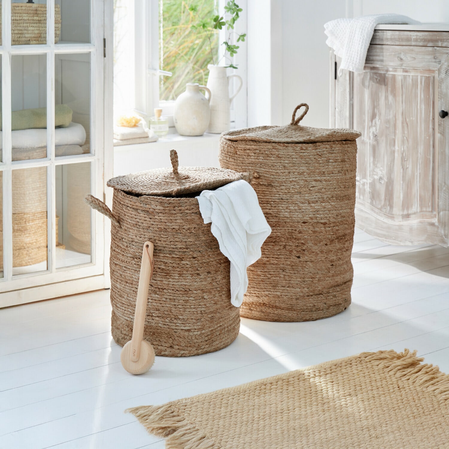 Wäschekorb 2er Set Kory Zwei runde Wäschekörbe aus natürlicher Jute in Beige in einem hellen Badezimmer